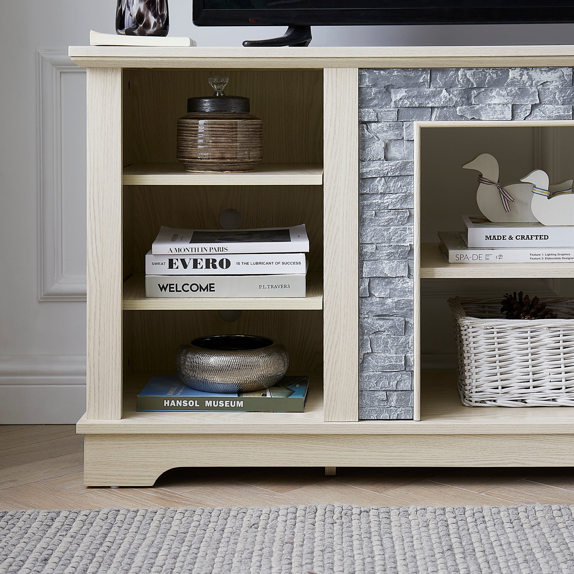 Light oak TV stand with grey stone accent displaying decorative items and books