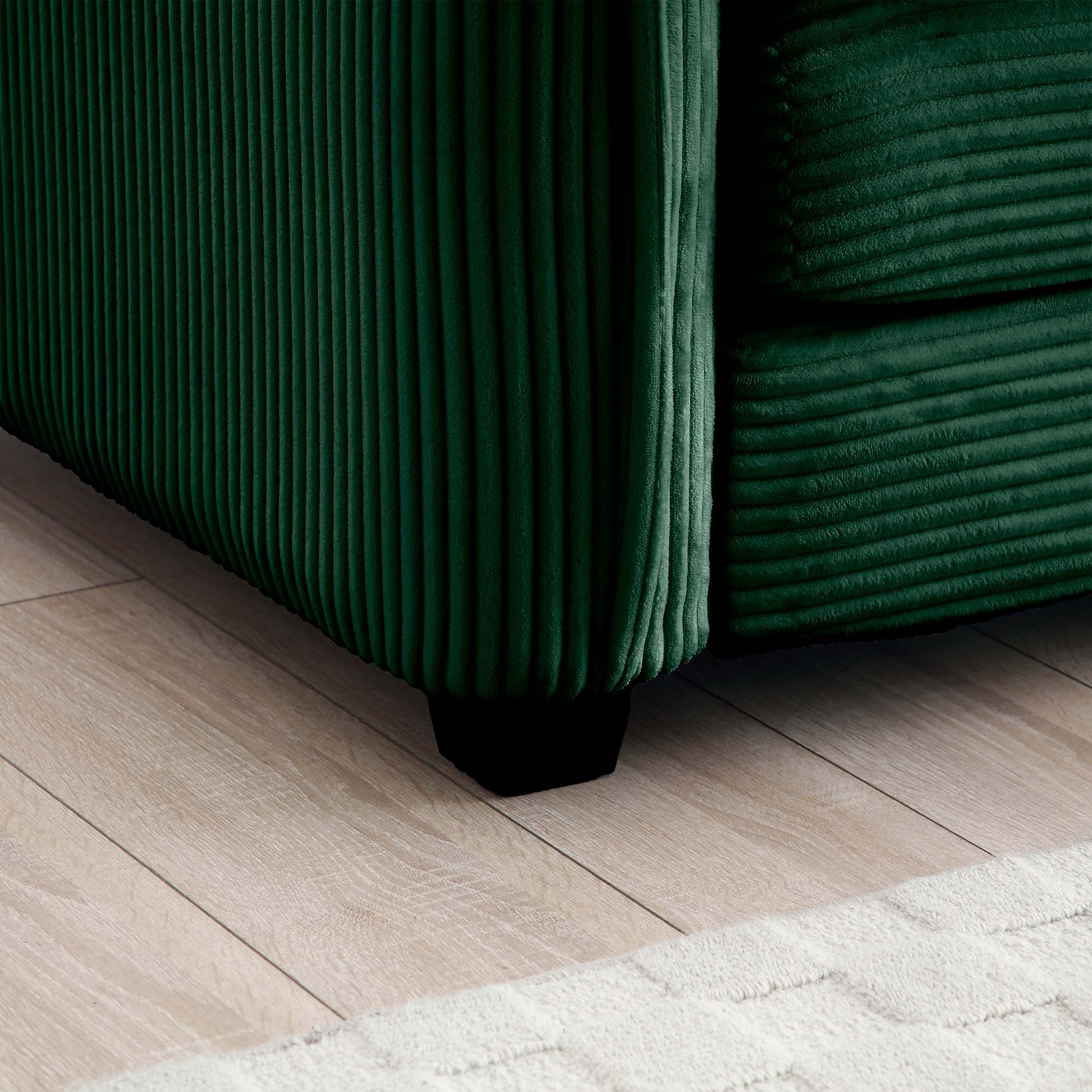 Deep green corduroy sofa detail with ribbed texture and black wooden foot