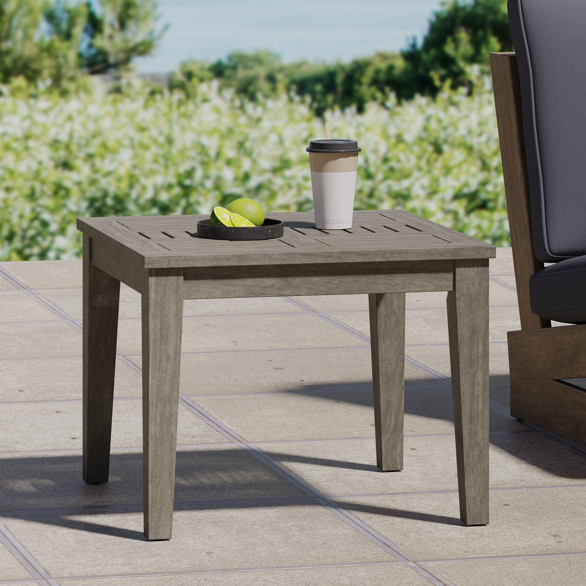Gray wooden slatted side table with carved legs on patio with drink and lime slices