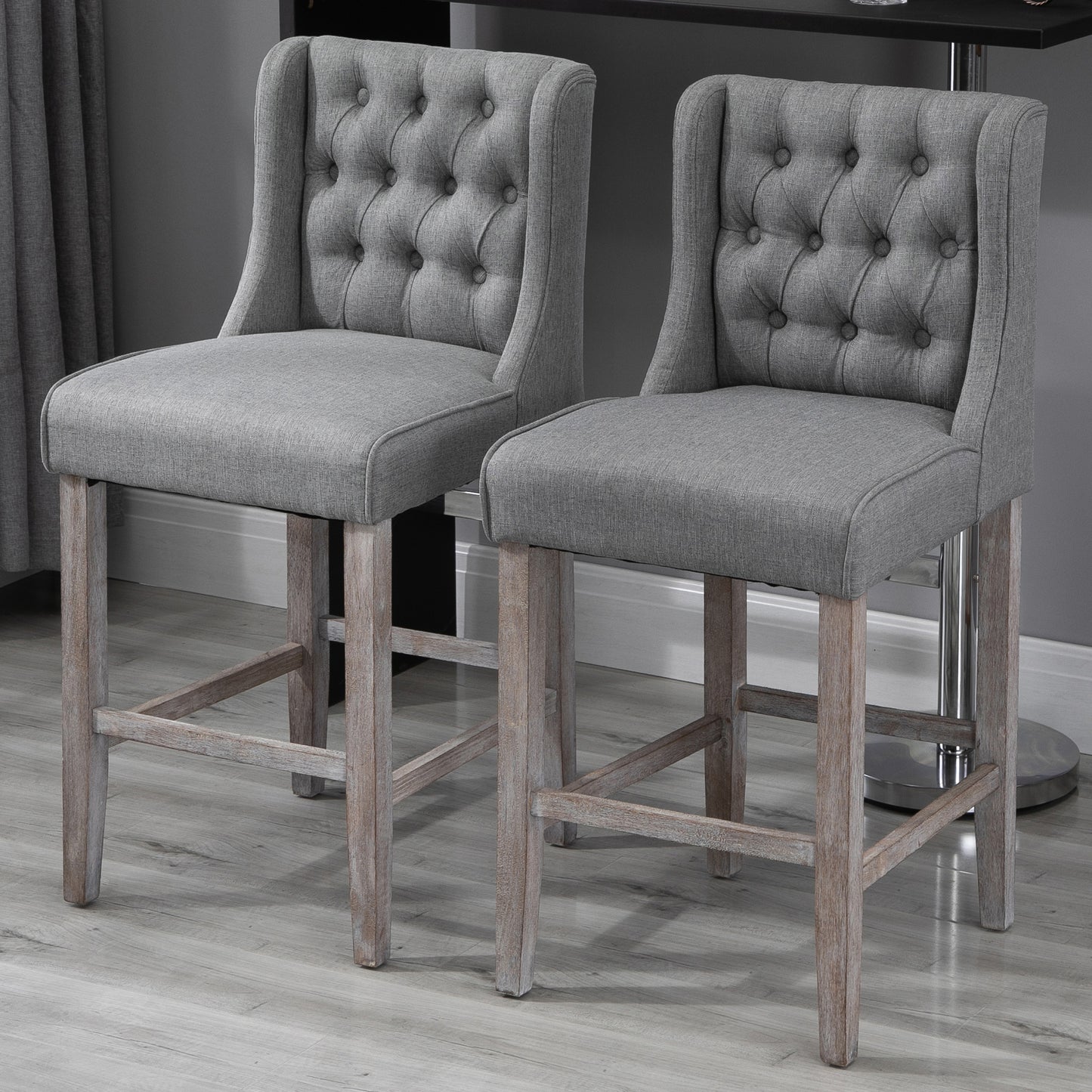 Pair of grey upholstered tufted back bar stools with distressed wood legs