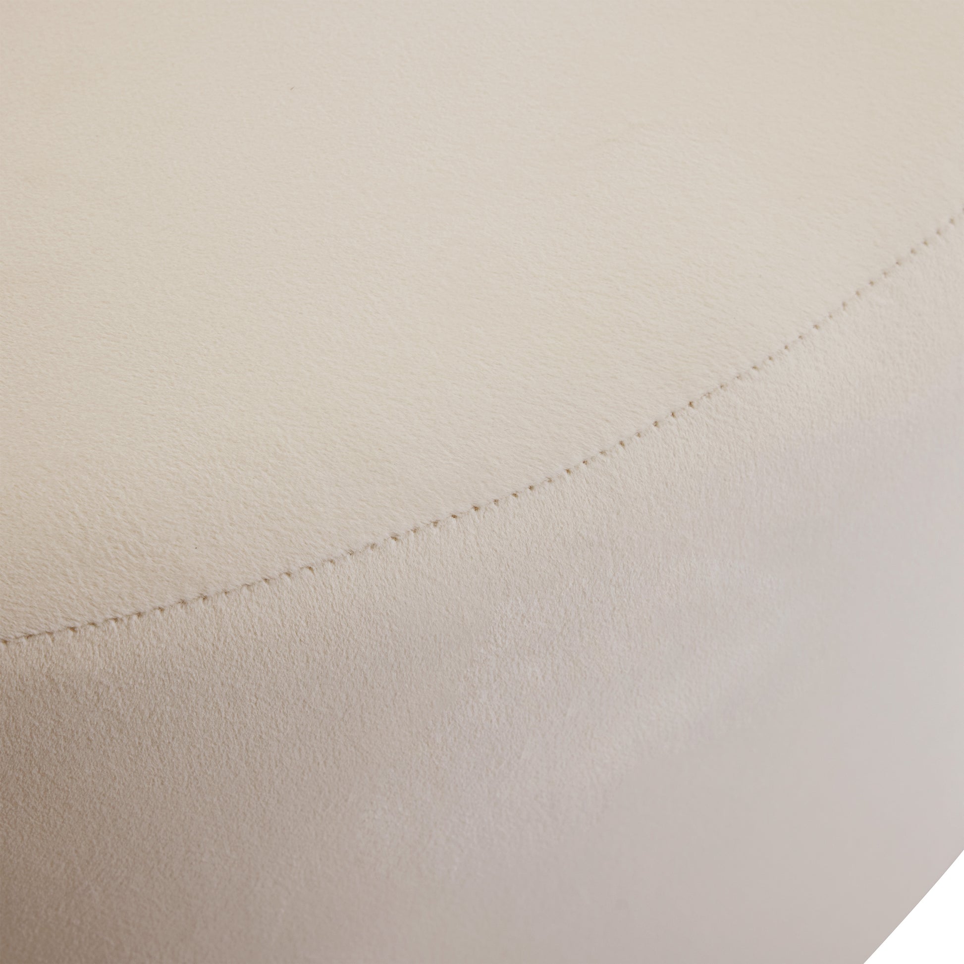 Closeup of a stitched seam on a textured light beige faux leather ottoman