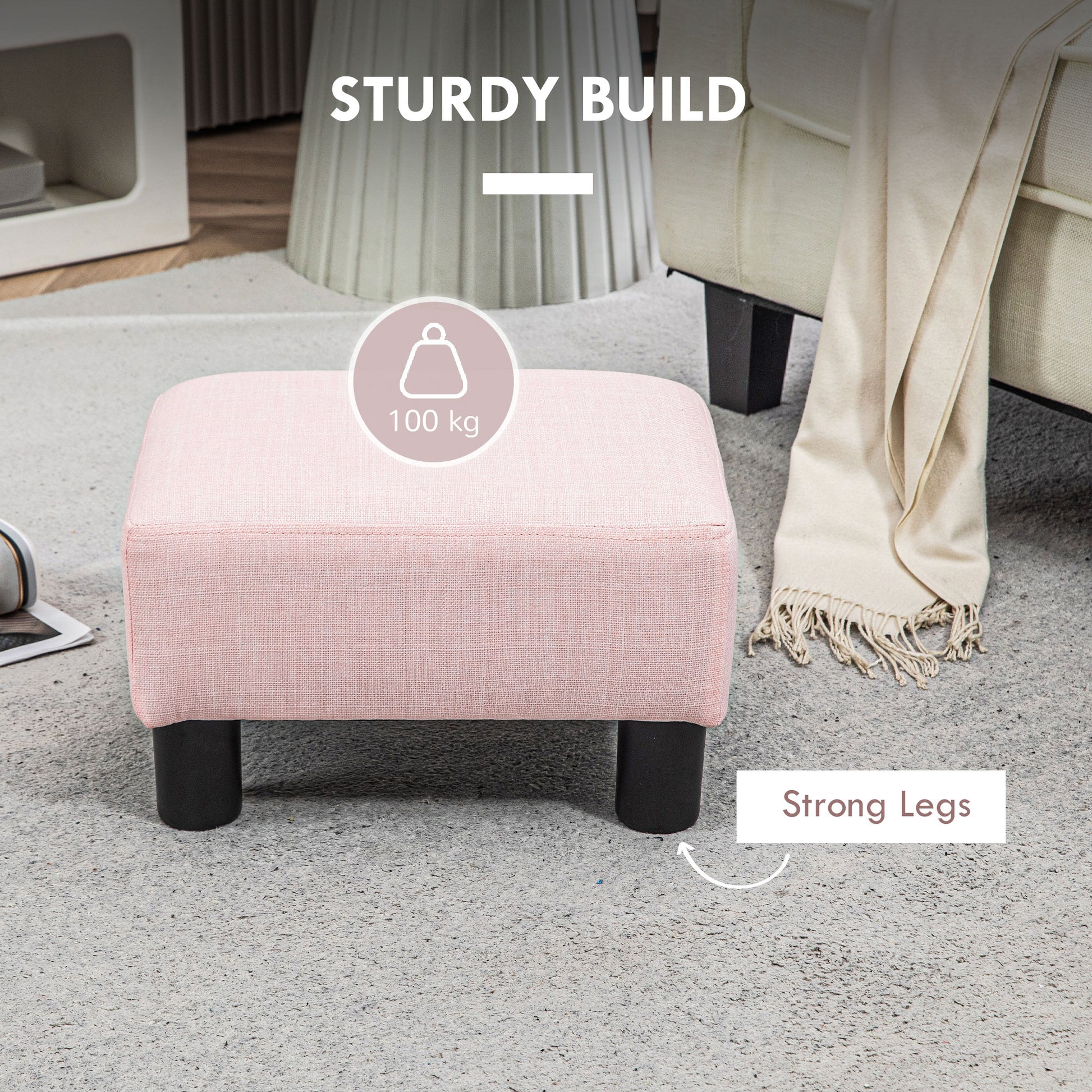 A square pink linen ottoman with black legs sits on a grey rug