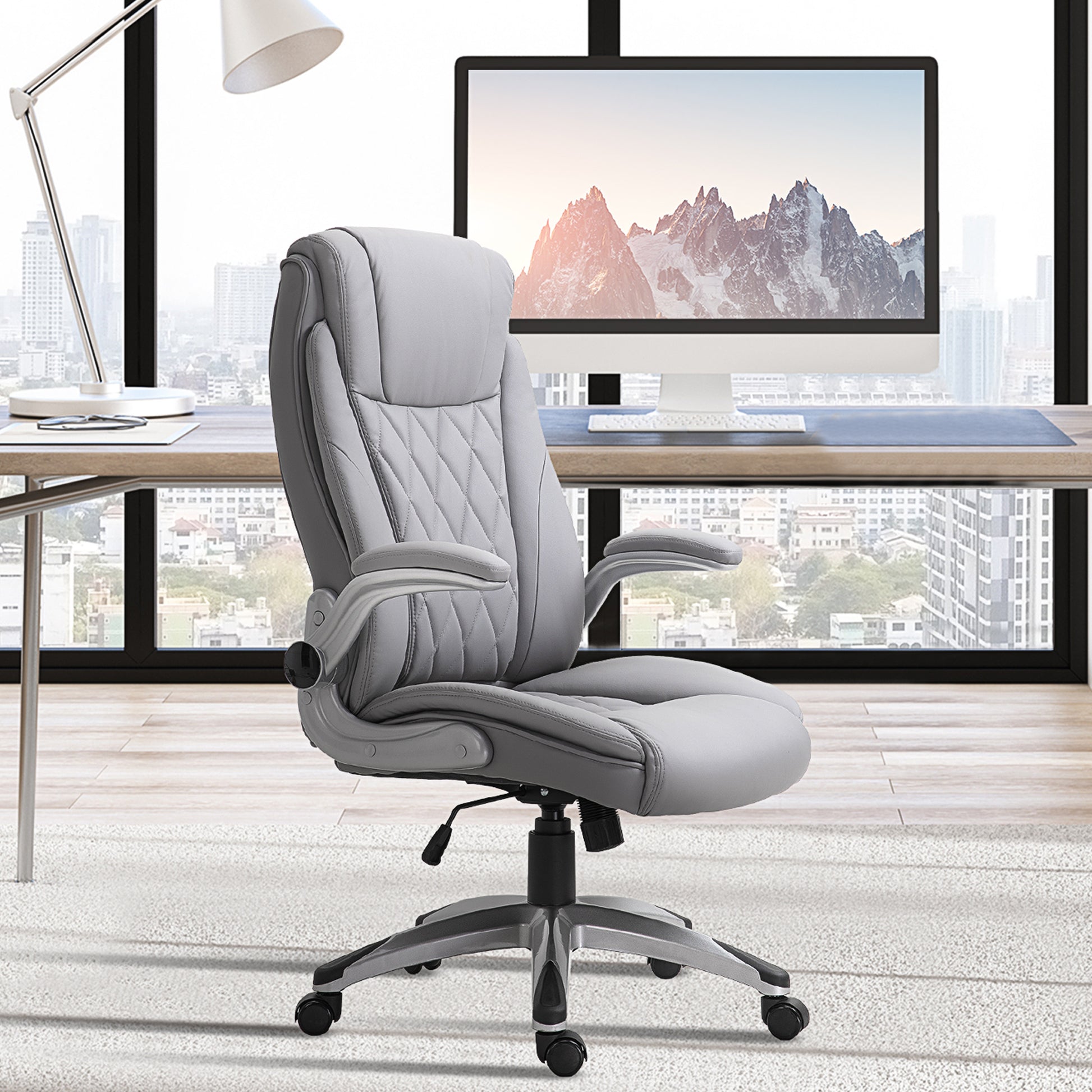 Executive office chair in light gray faux leather with quilted stitching and padded armrests