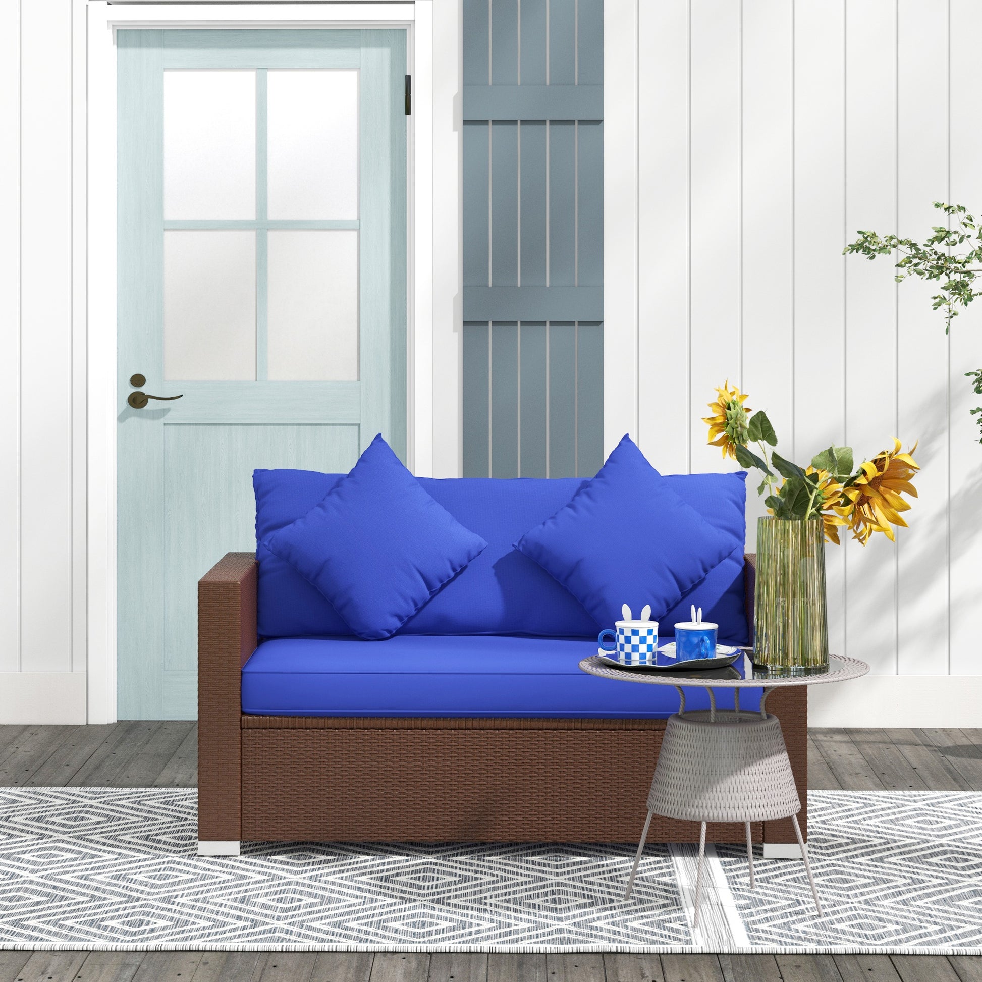 Brown wicker outdoor loveseat with royal blue cushions and throw pillows