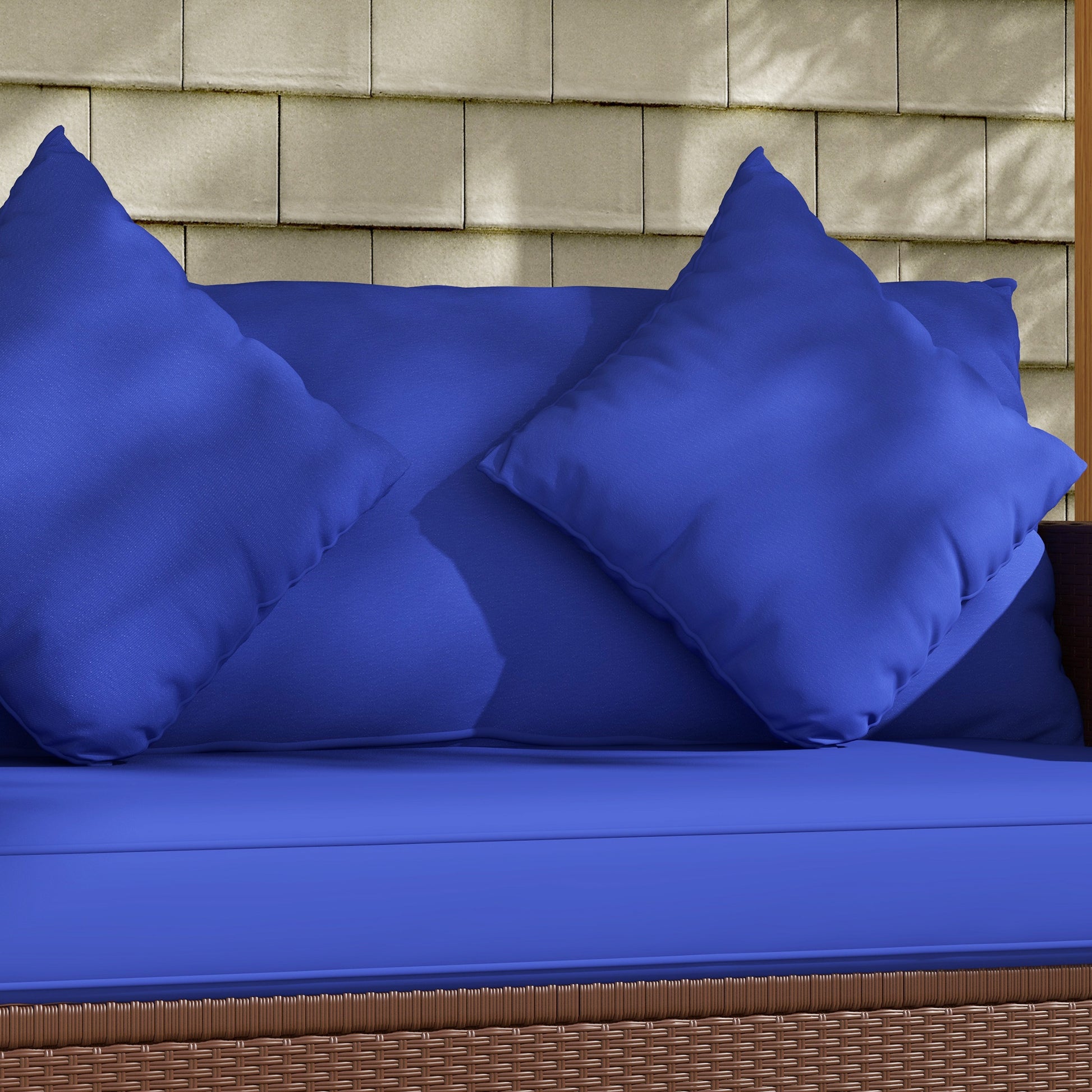Plush royal blue outdoor sofa cushions with detailed stitching and a woven wicker base
