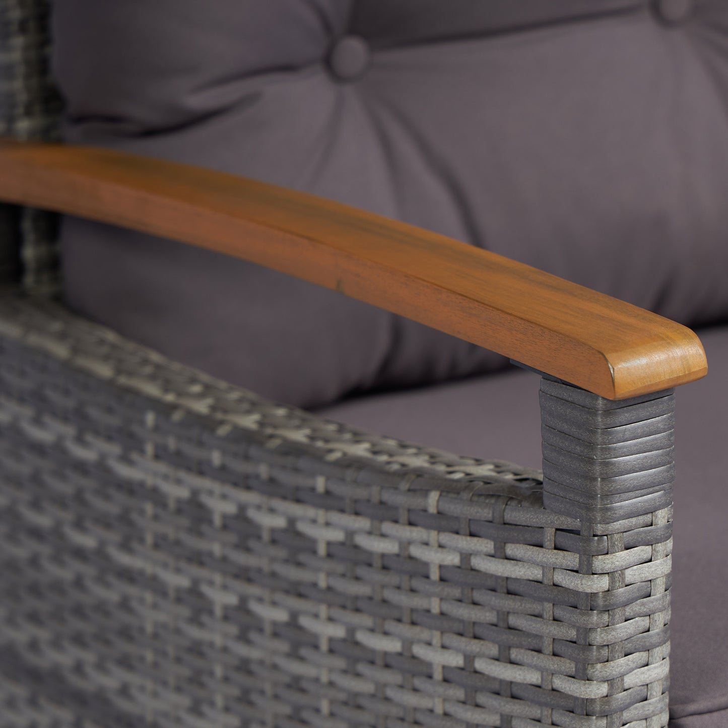 Closeup of a grey rattan armchair armrest with a wooden accent and cushion