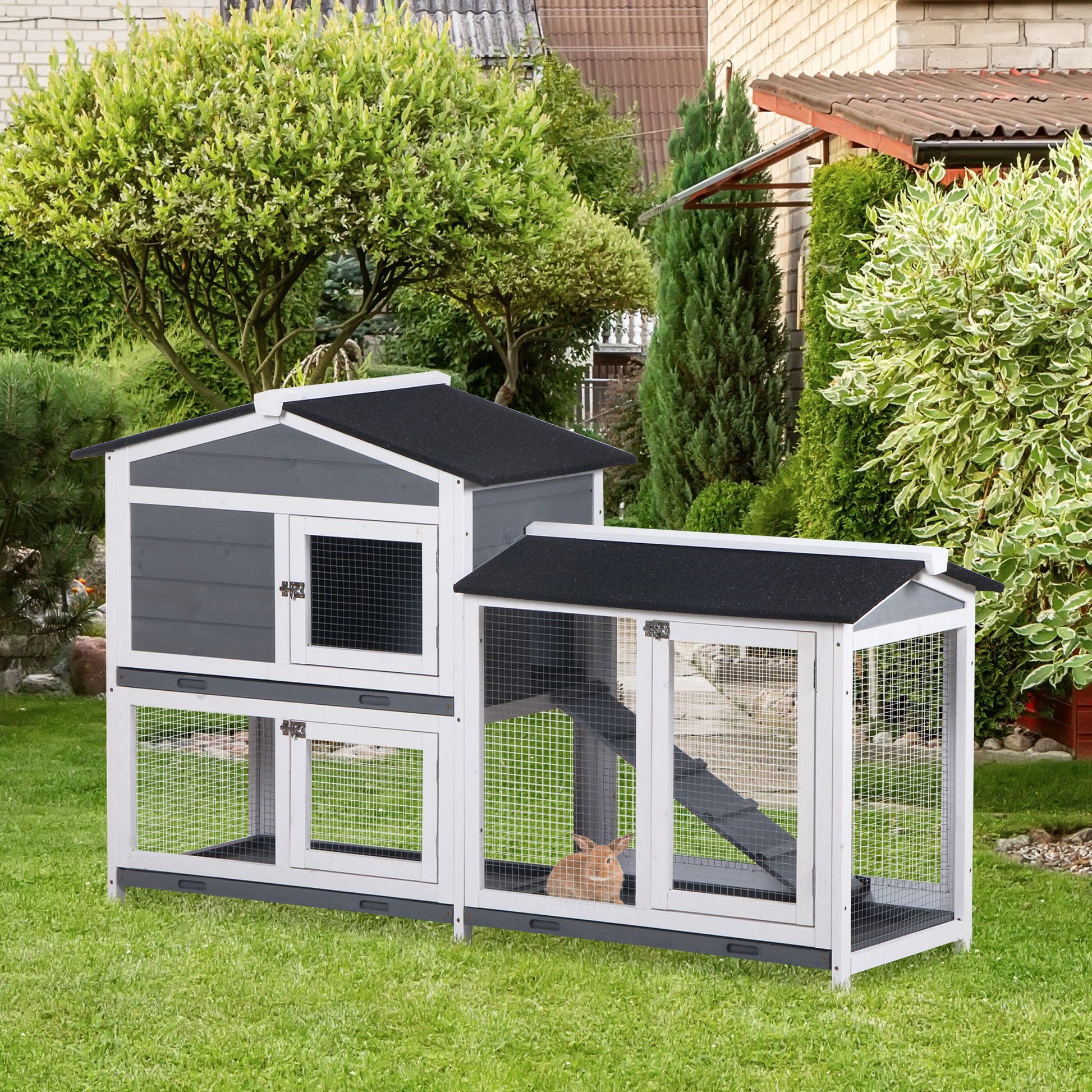 Twotier grey and white wooden rabbit hutch with wire mesh doors and a ramp set on a green lawn