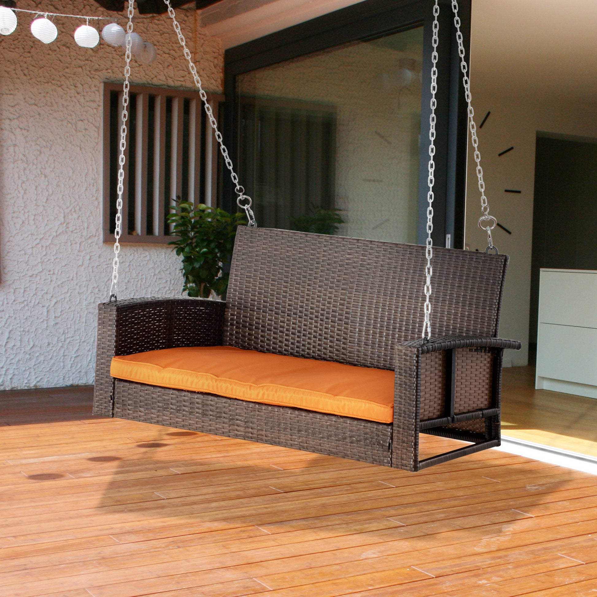 Brown wicker patio swing with bright orange cushion perfect for outdoor relaxation