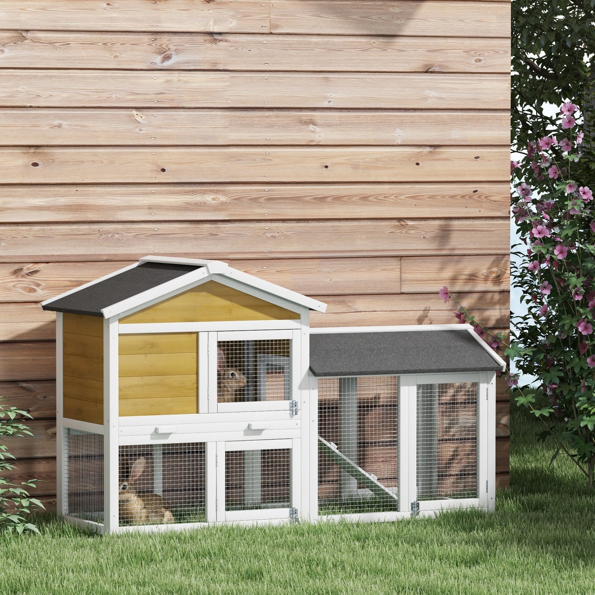 Twotier wooden rabbit hutch with yellow siding and wire mesh doors on grass