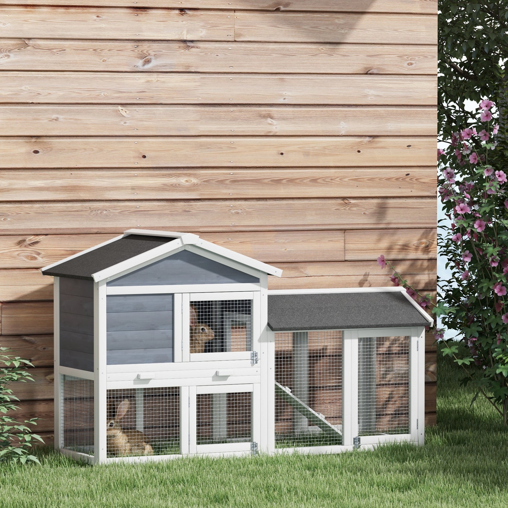 Twostory gray and white rabbit hutch with wire mesh doors on a grassy lawn