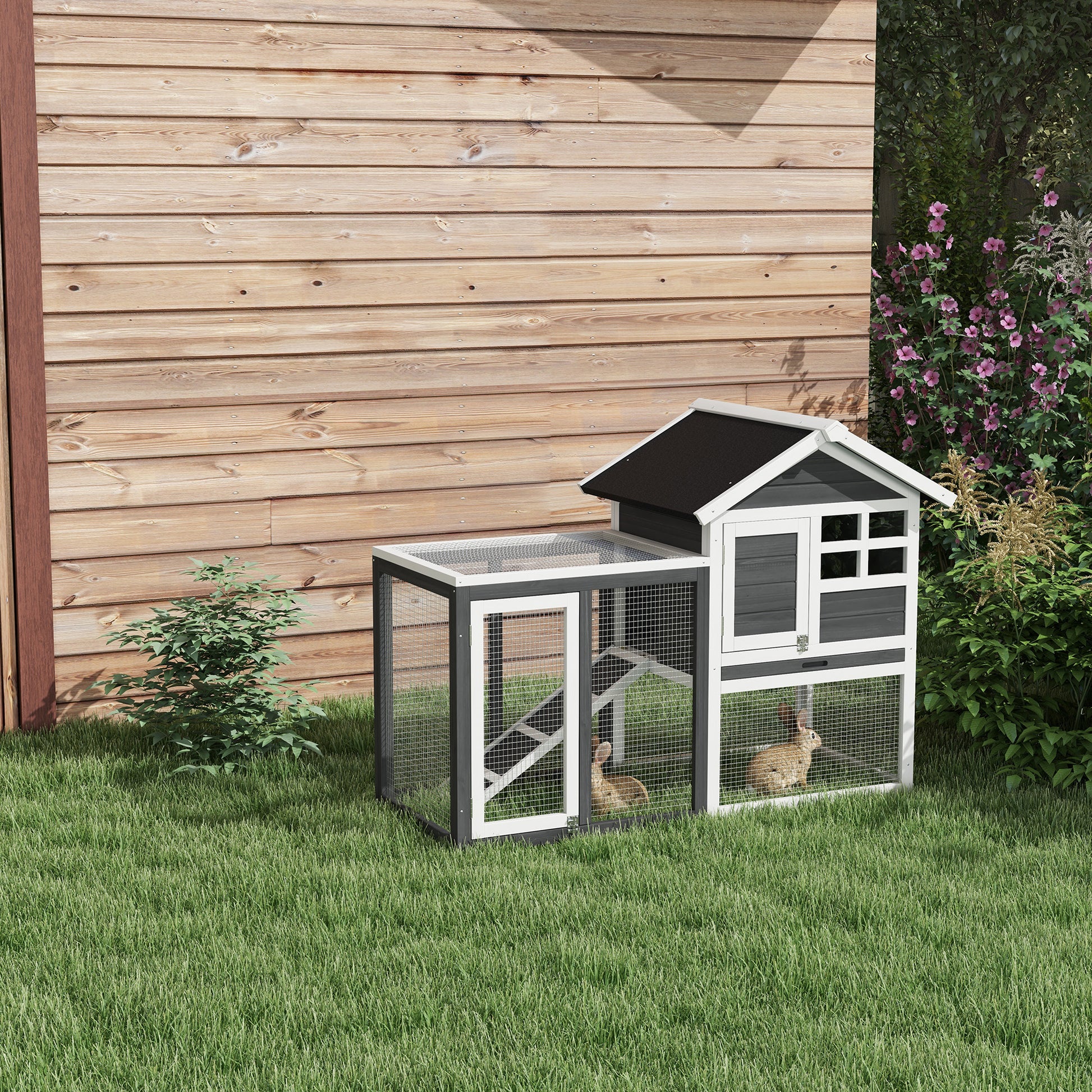 Twotier grey and white wooden rabbit hutch with run and two brown rabbits on grass