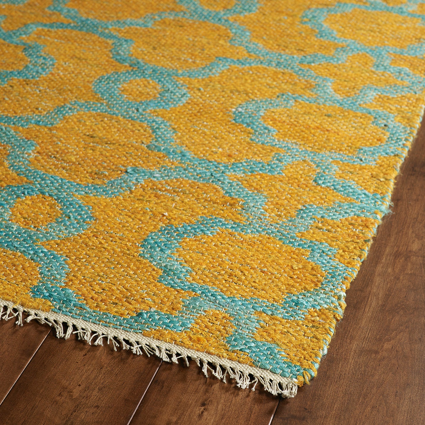 Closeup of a textured woven rug with a geometric pattern in mustard yellow and turquoise blue
