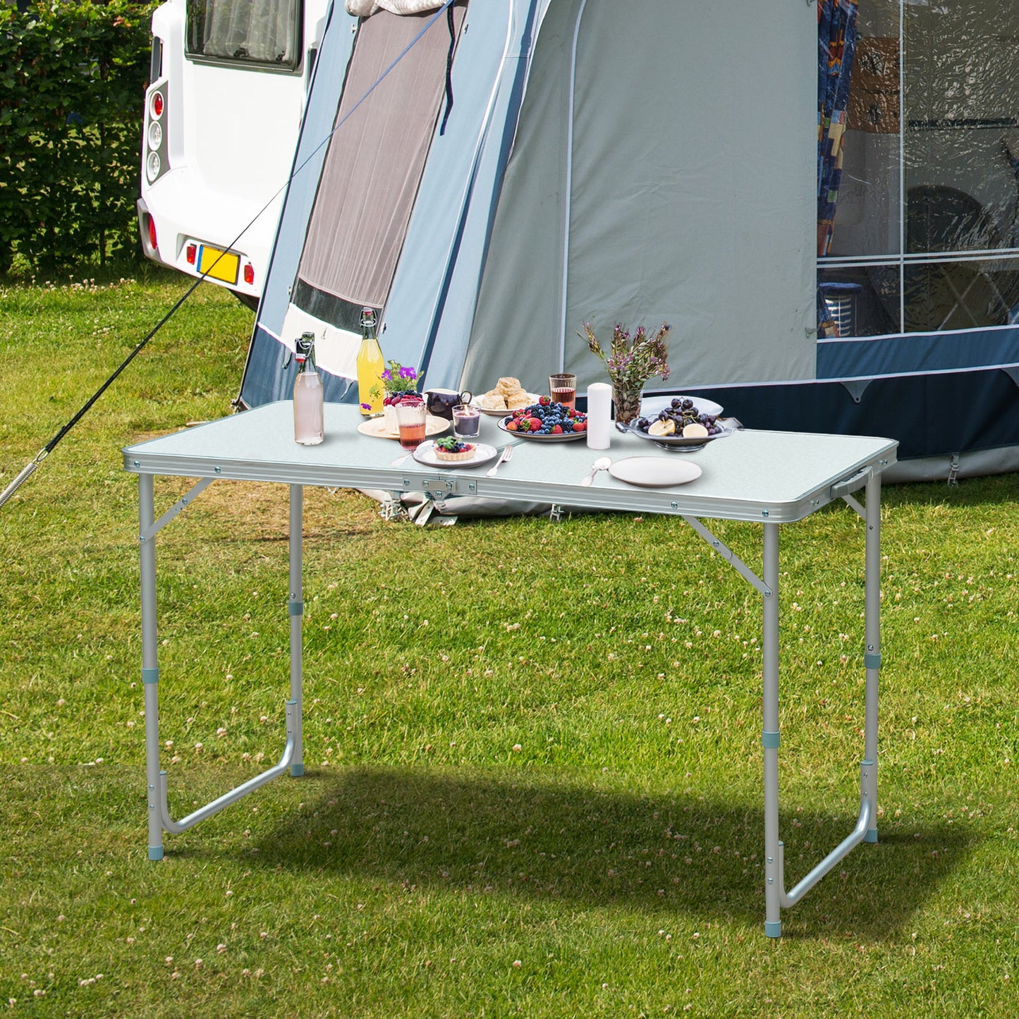 Lightweight aluminum folding table set up on grassy campsite ready for picnic