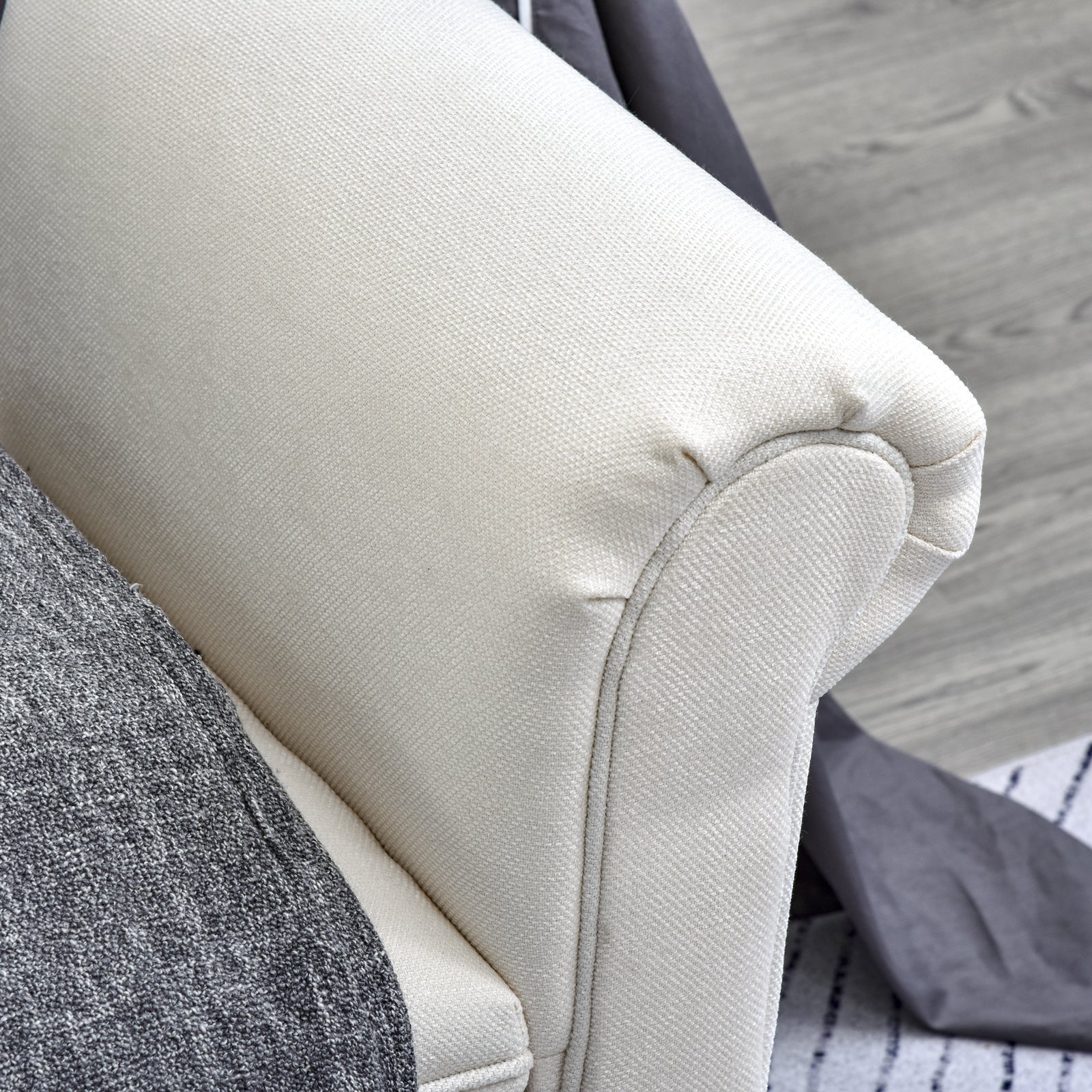 Cream textured fabric armchair armrest with grey throw blanket detail