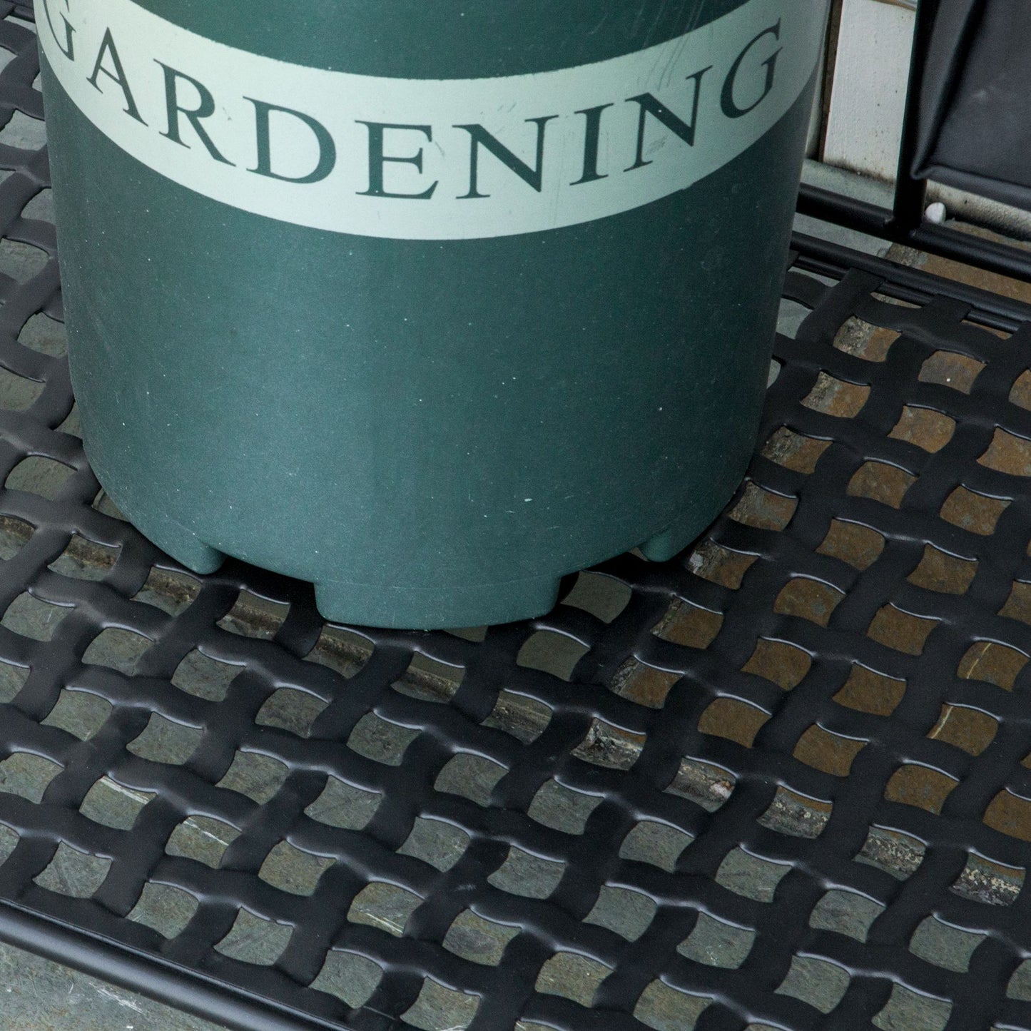 Green gardening pot with white lettering on metal grate stand
