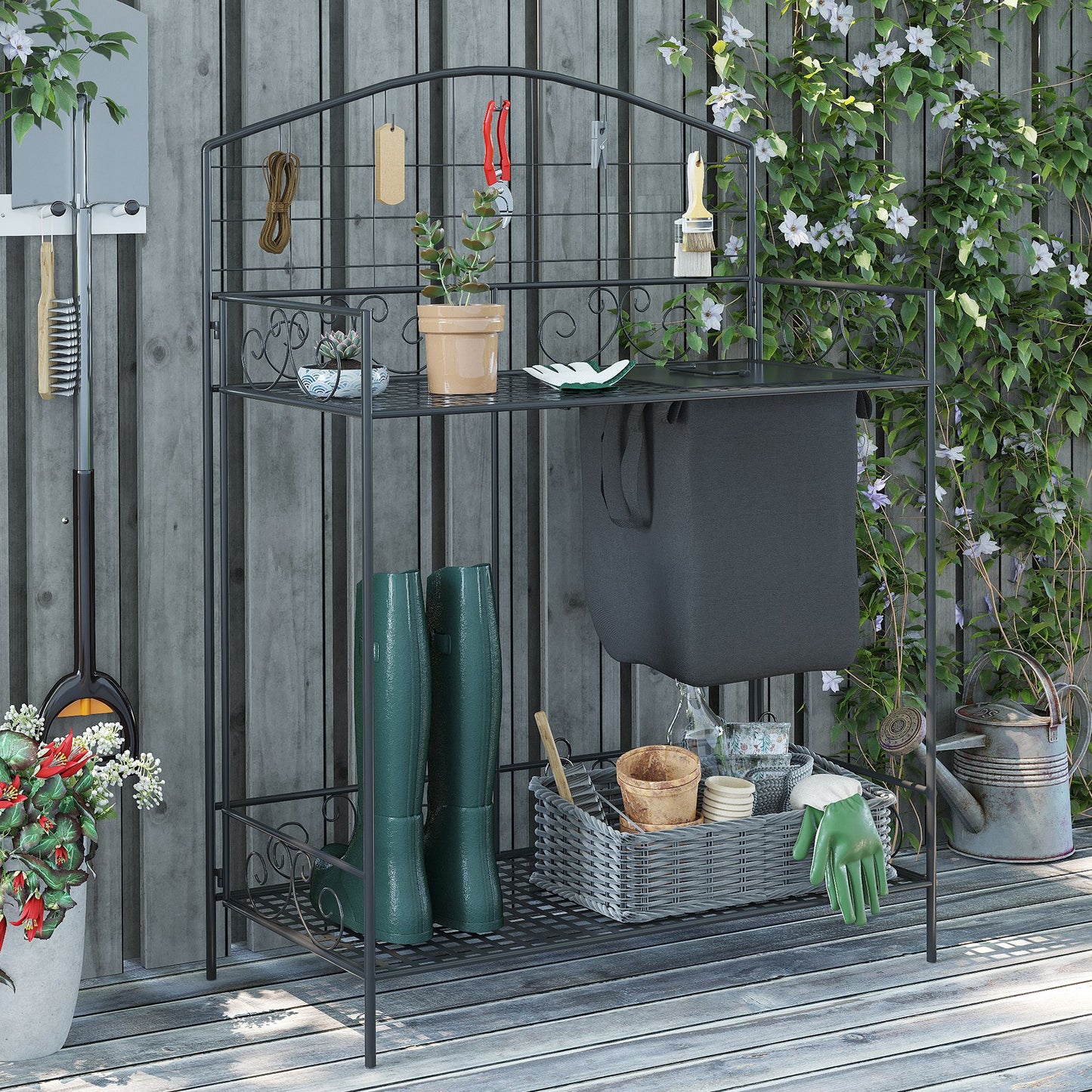 Black metal garden potting bench with green boots watering can and gardening tools