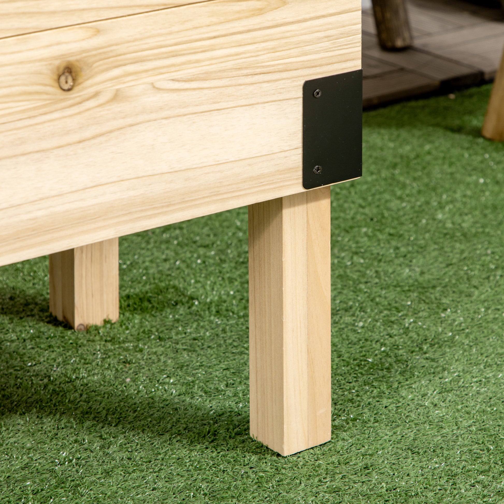 Wooden raised garden bed with black corner brackets resting on artificial turf