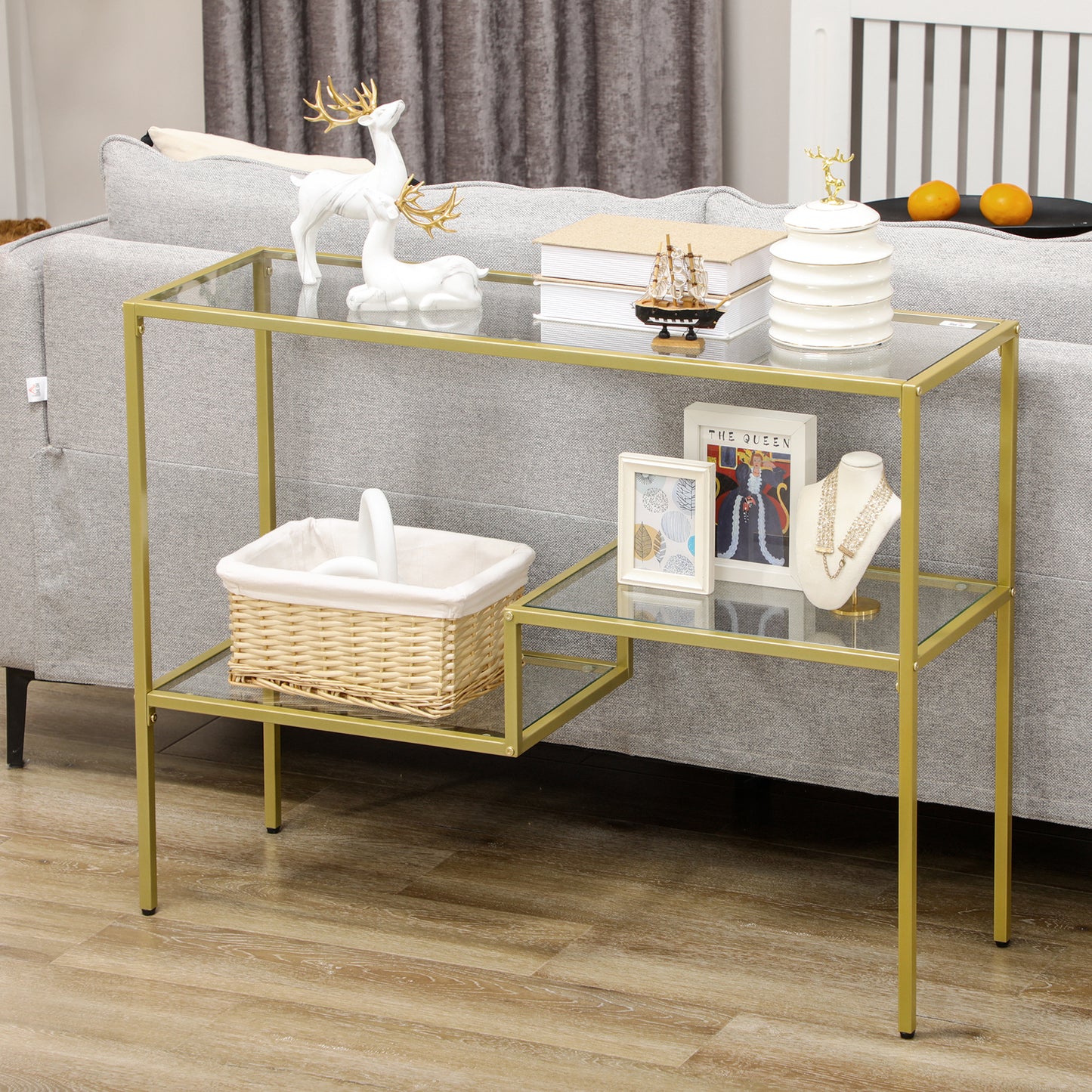 Gold metal console table with glass shelves holding decorative items like deer figurines