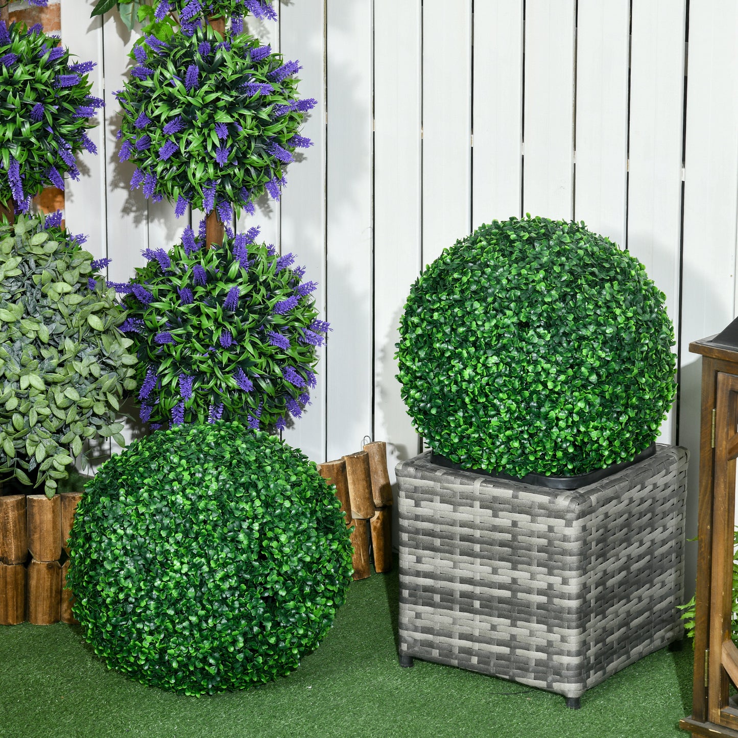 Green faux boxwood topiary sphere on a grey rattan planter for outdoor decor
