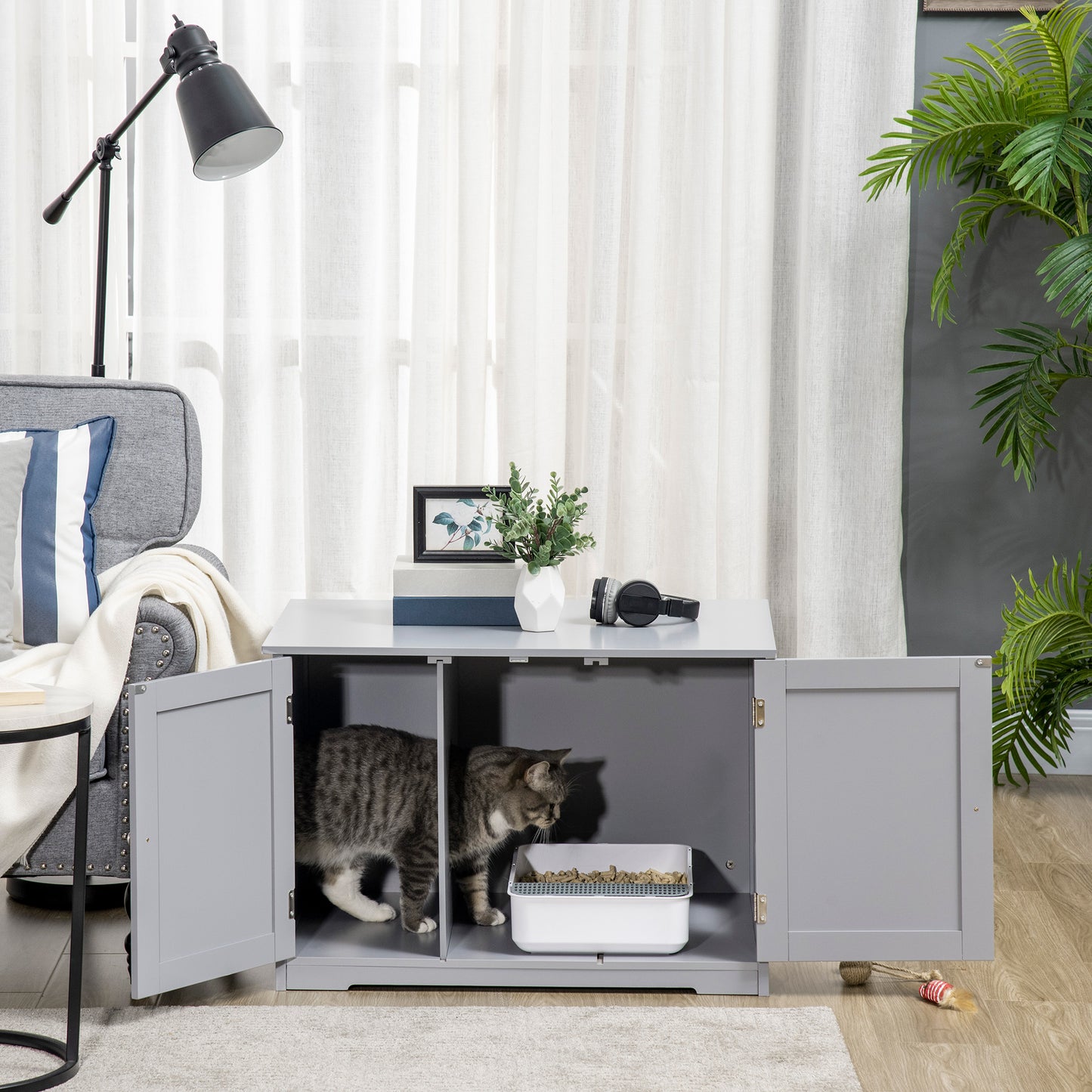 Grey wooden cat litter box enclosure with two internal compartments and a tabby cat entering one