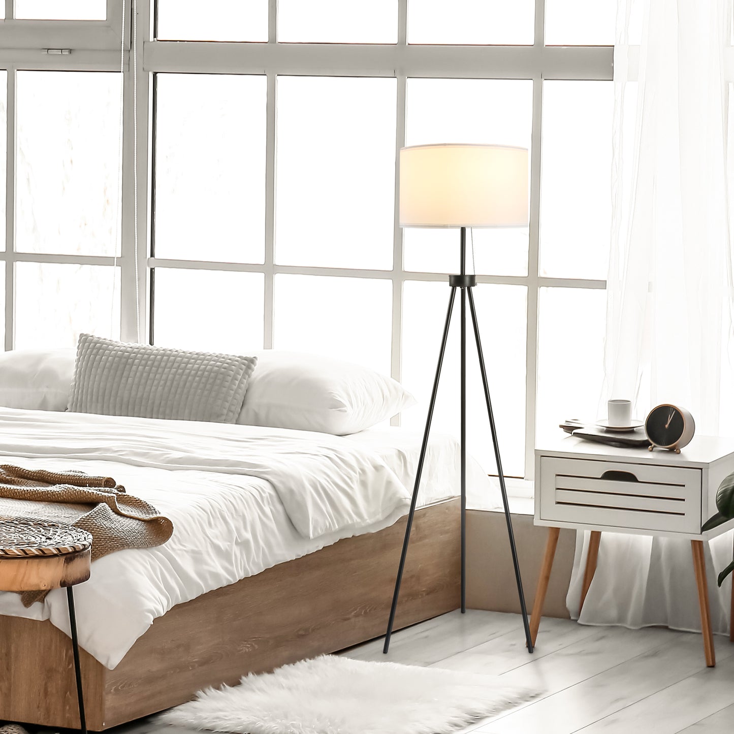 Modern black tripod floor lamp with white drum shade providing ambient lighting