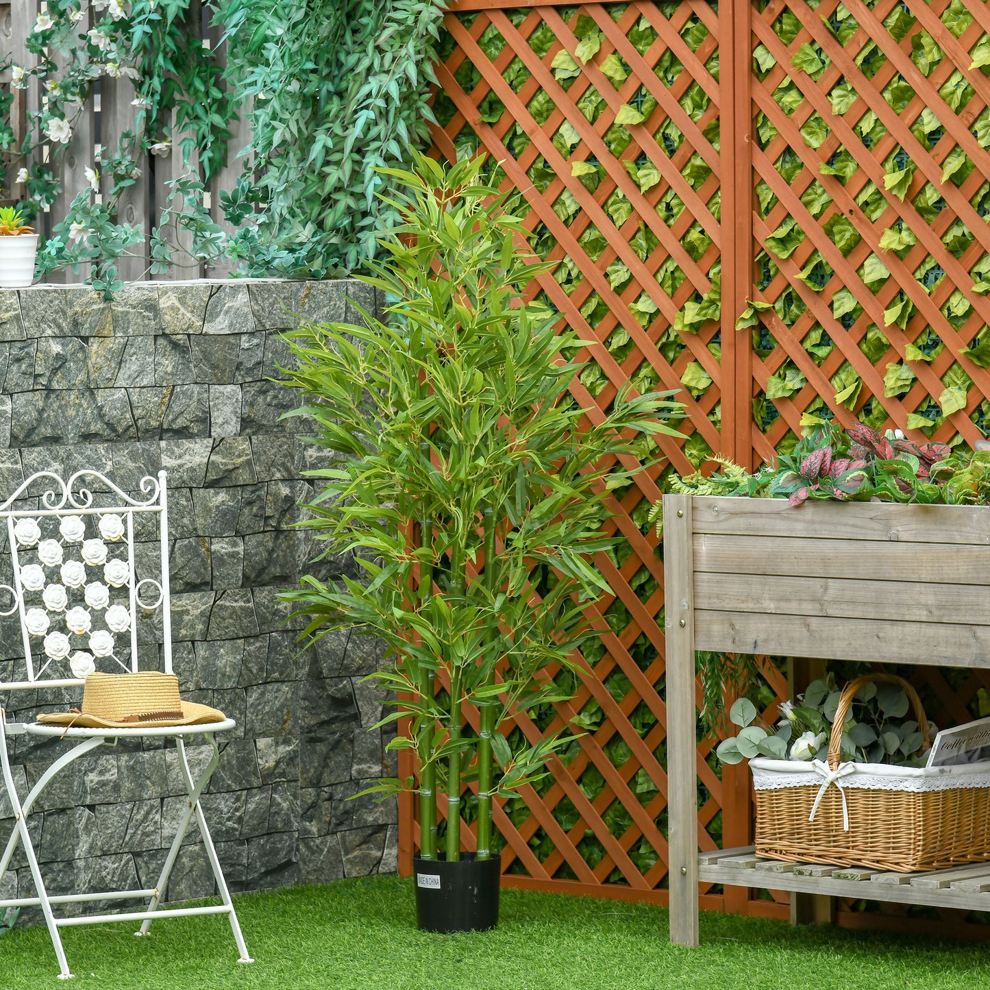 Tall artificial bamboo plant with green stalks and leaves in a black pot