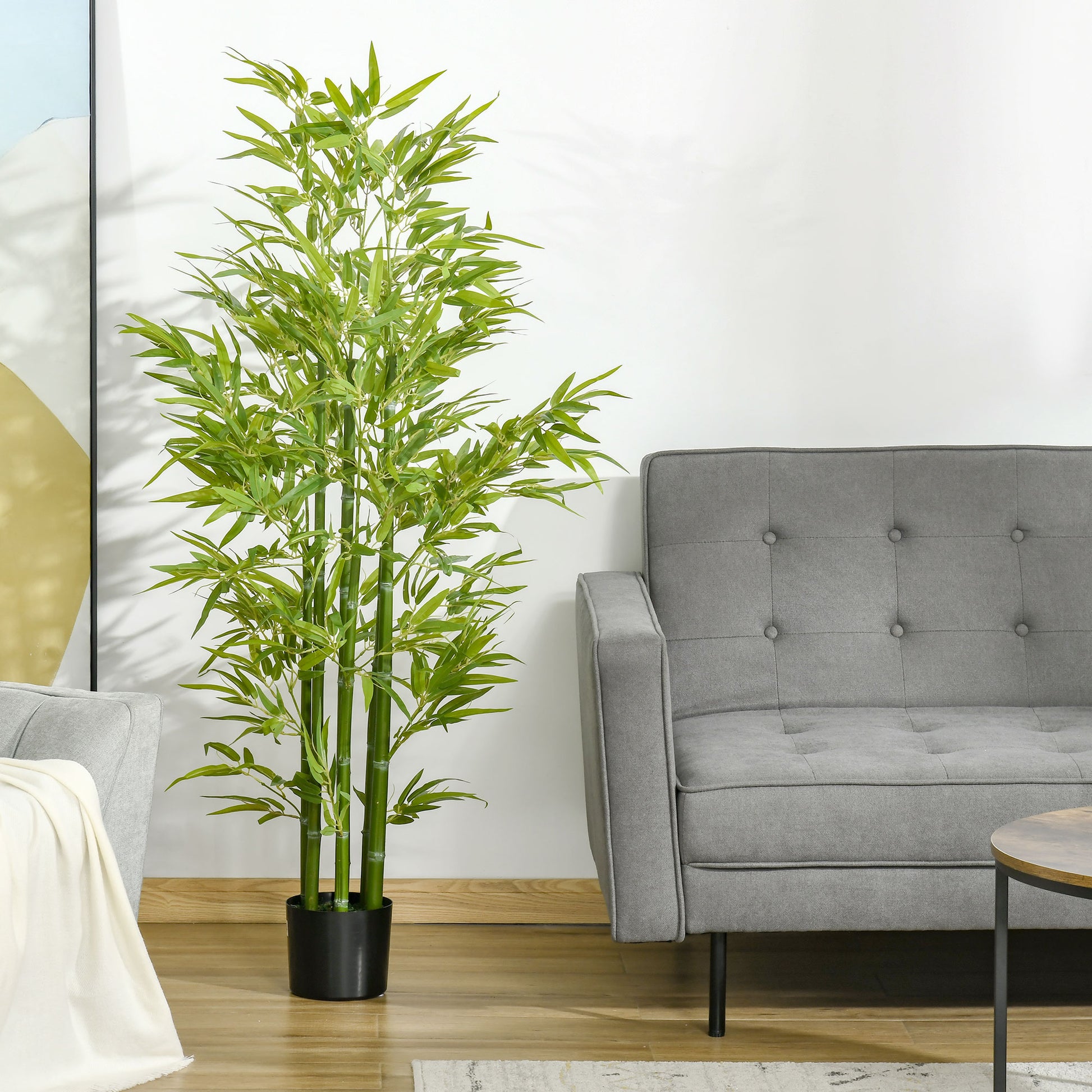 Tall artificial bamboo plant with green stalks and leaves in a black pot ideal for indoor decor