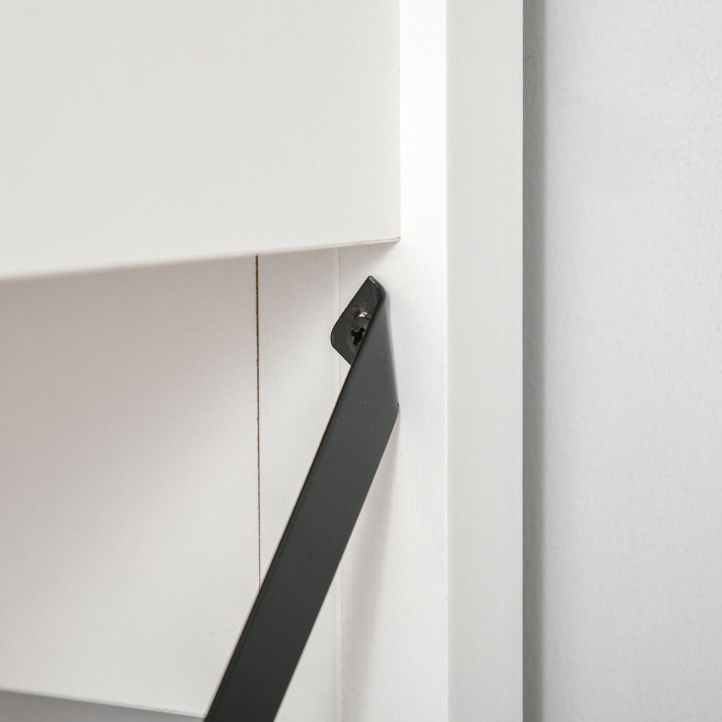 Closeup of a black metal shelf bracket on a white shelf unit