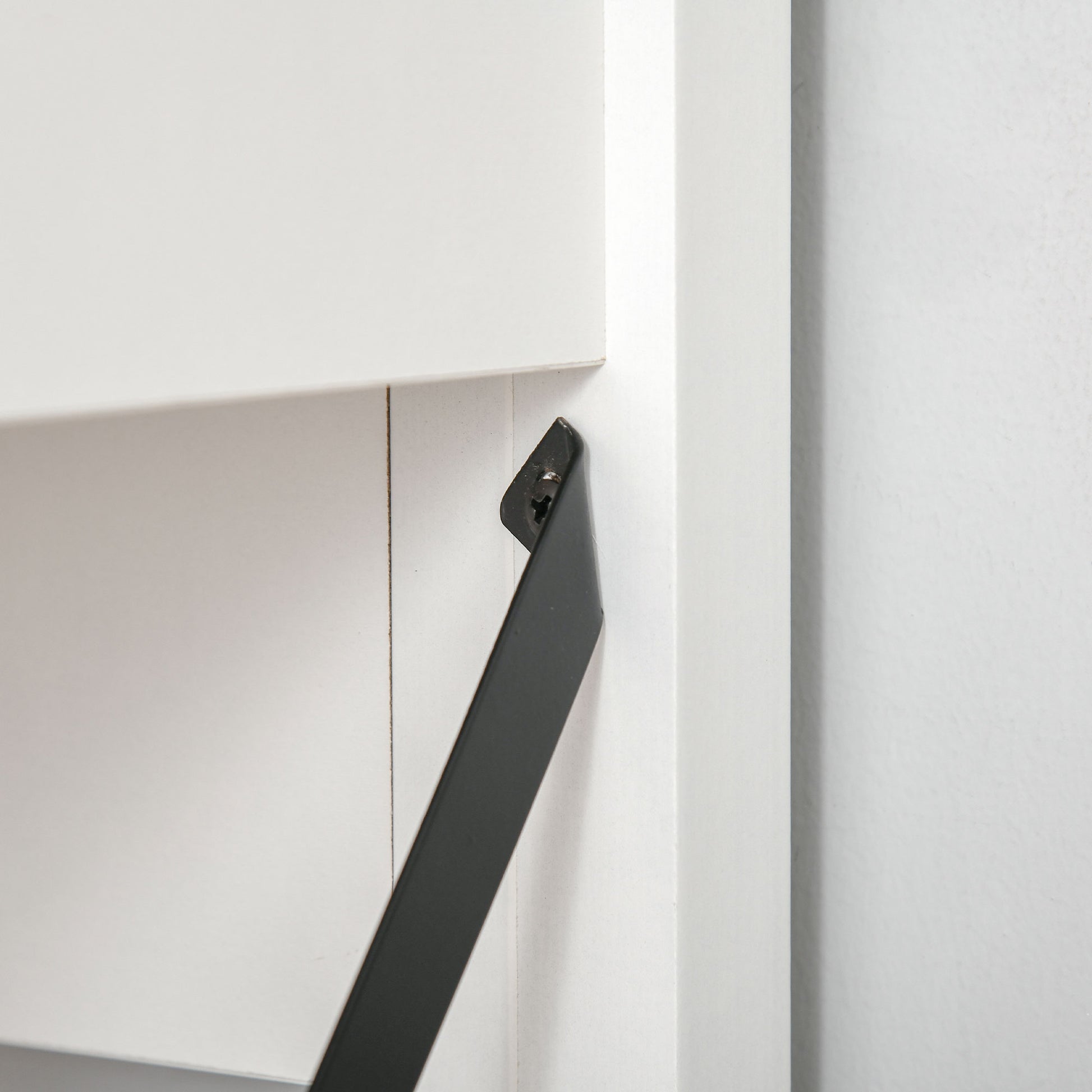 Closeup of a black metal shelf bracket on a white shelf unit