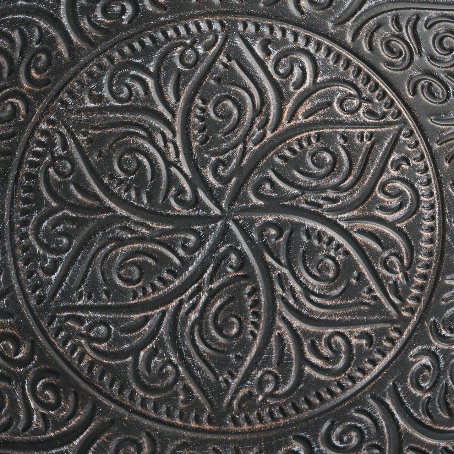 Closeup of dark brown metal inlay with ornate floral scrollwork design
