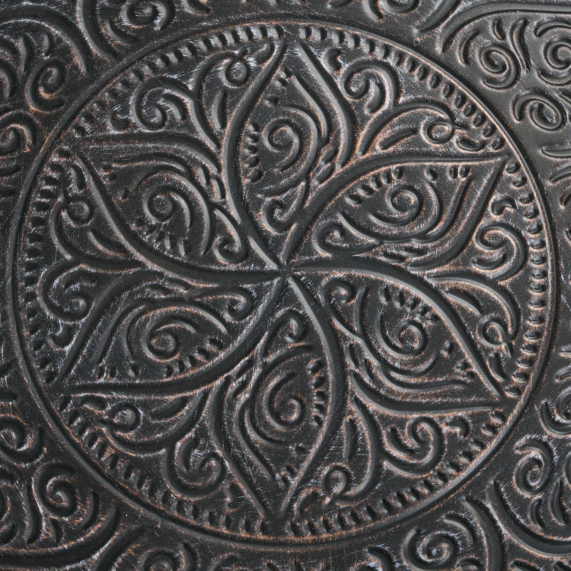 Closeup of dark brown metal inlay with ornate floral scrollwork design