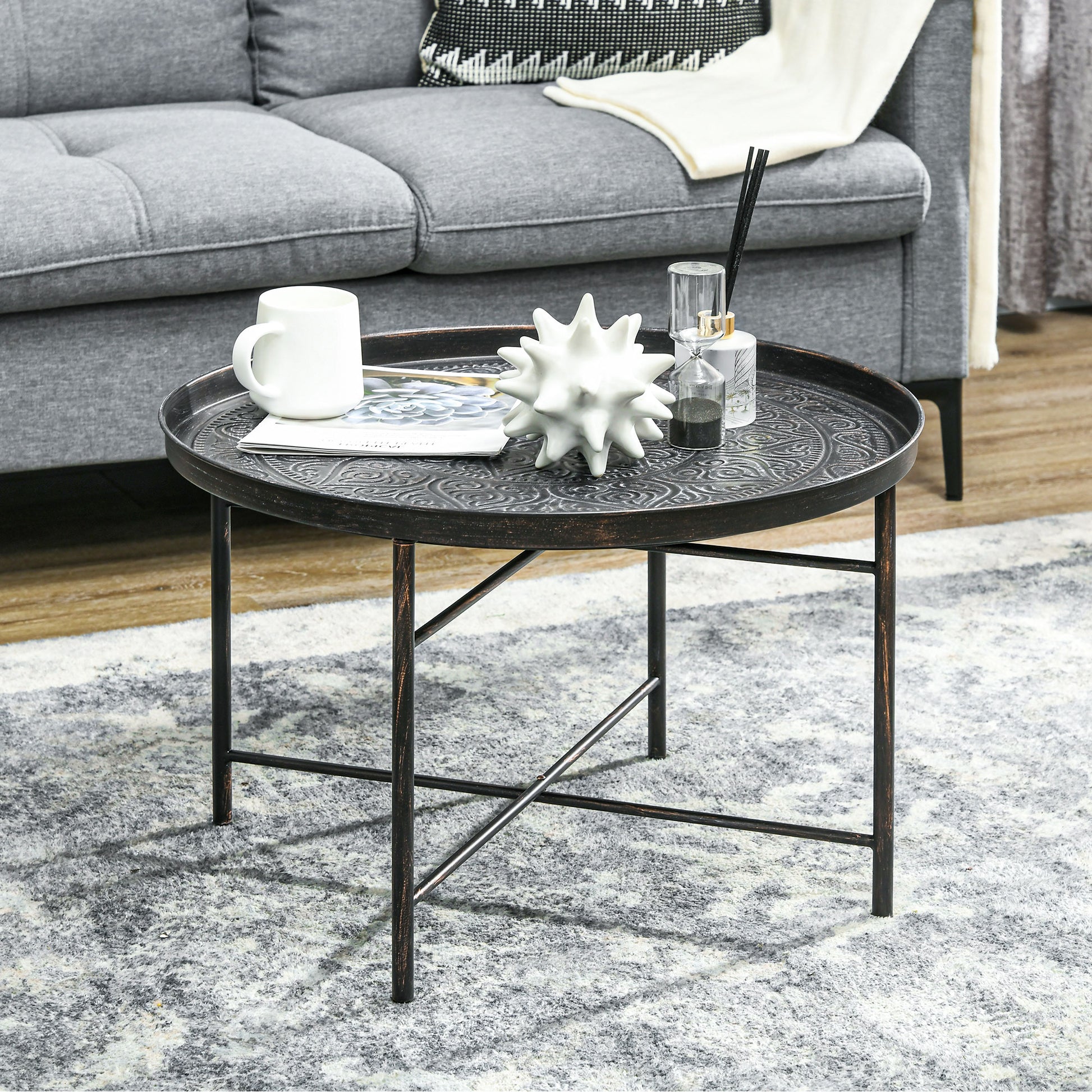 Antique brass round coffee table with embossed metal top and black legs