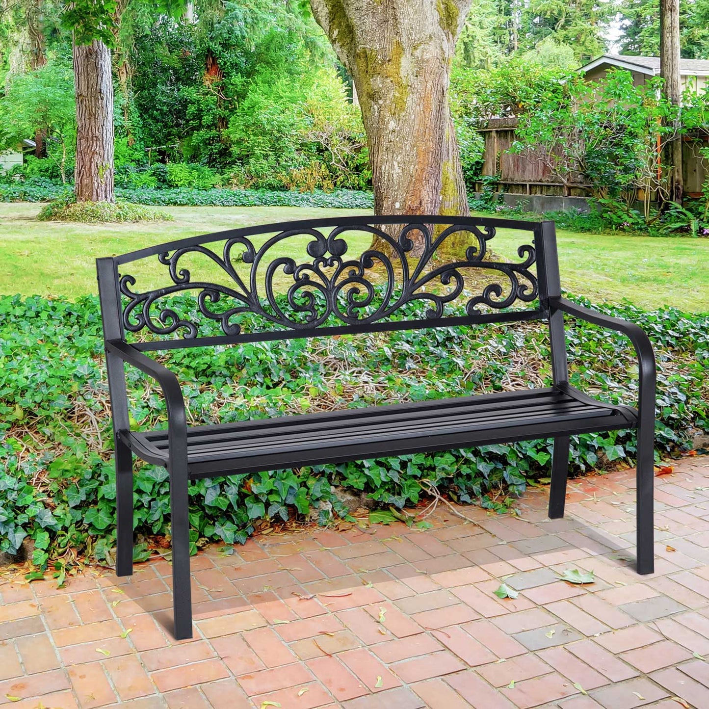 Black ornate metal garden bench with decorative backrest on brick patio