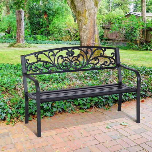 Black ornate metal garden bench with decorative backrest on brick patio