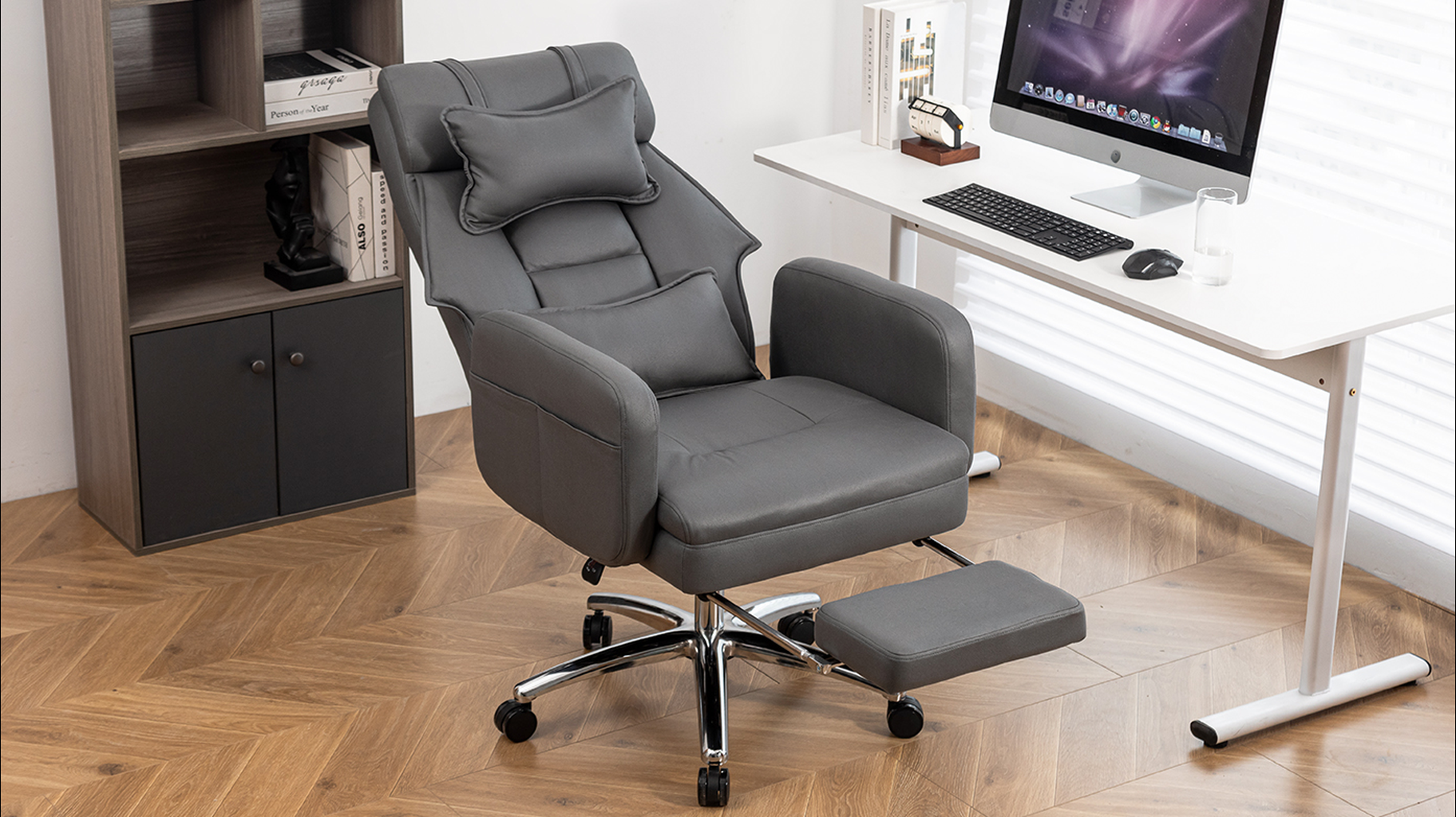 Dark gray faux leather office chair with adjustable footrest and lumbar pillow