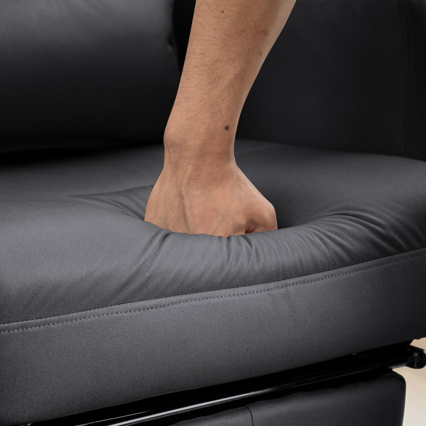 Closeup of a hand sinking into plush black faux leather upholstery on a modern chair