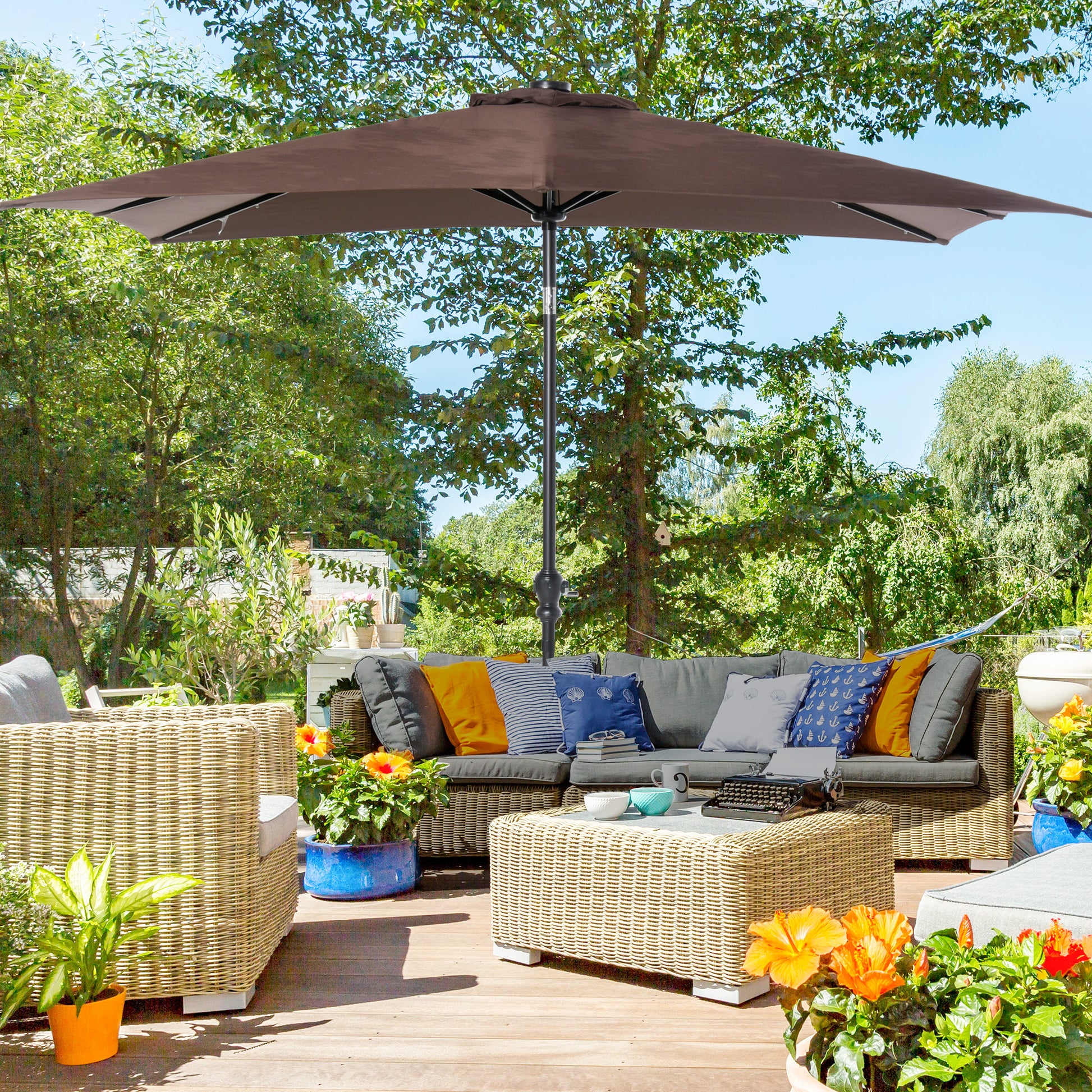 Brown patio umbrella provides shade for outdoor wicker sectional furniture and coffee table