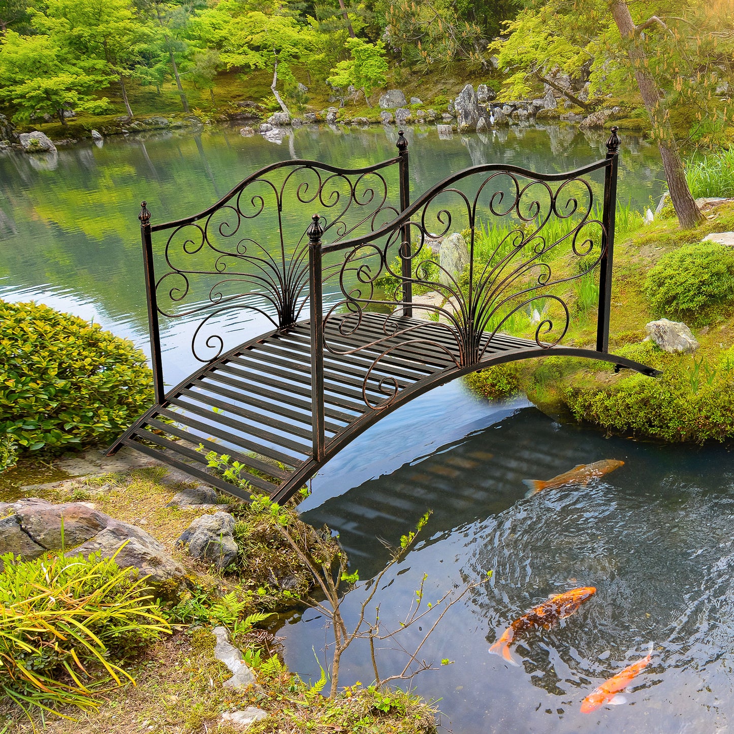 Black wrought iron garden bridge with ornate scrolling details over a pond