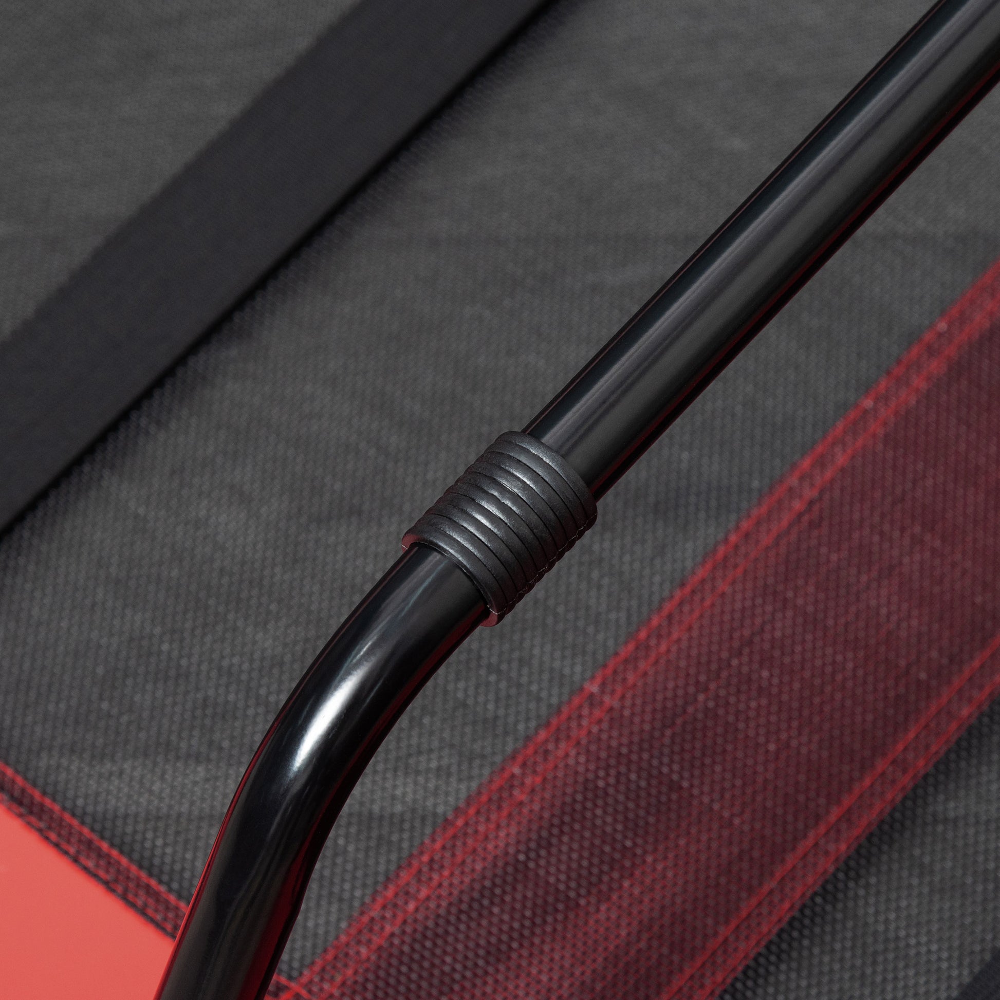 Closeup of black metal tubing with ribbed grip on a textured grey fabric background