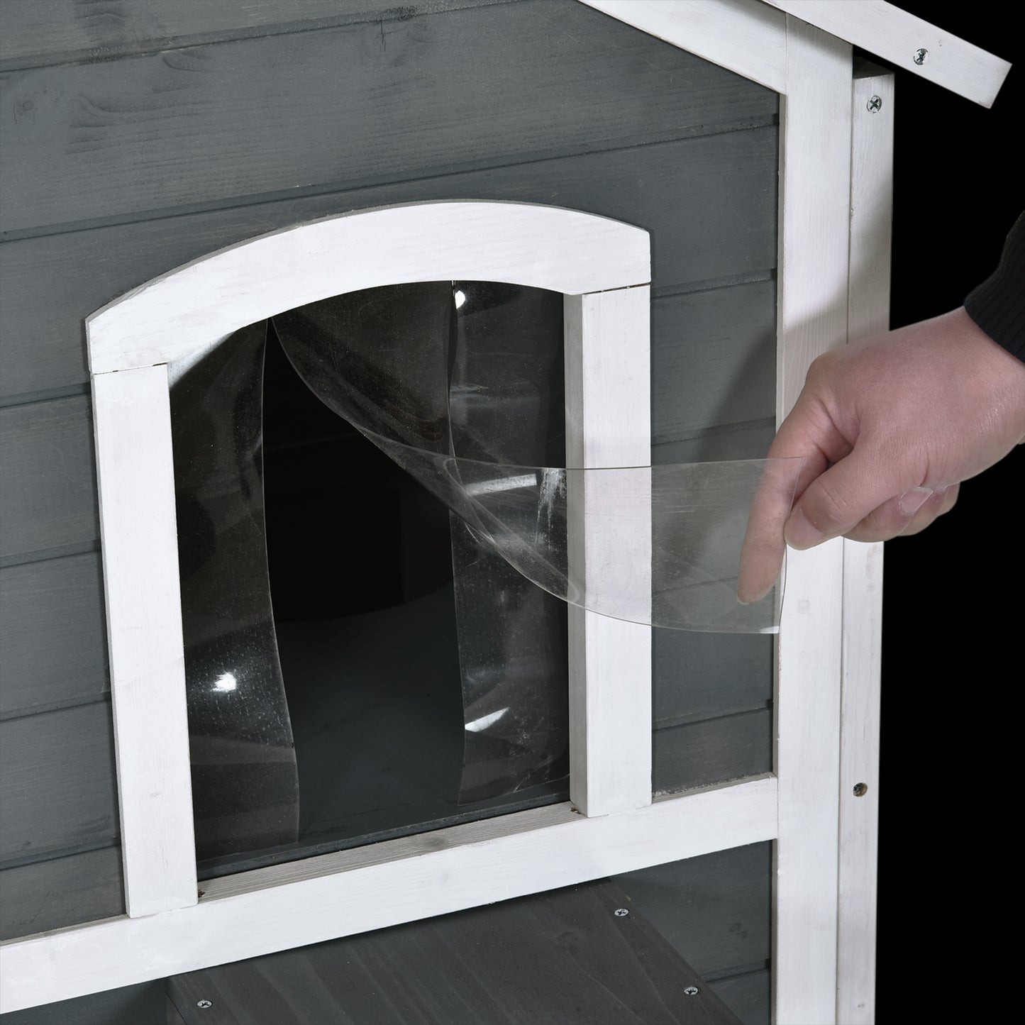 Grey wooden pet house door flap being attached with clear plastic weather stripping