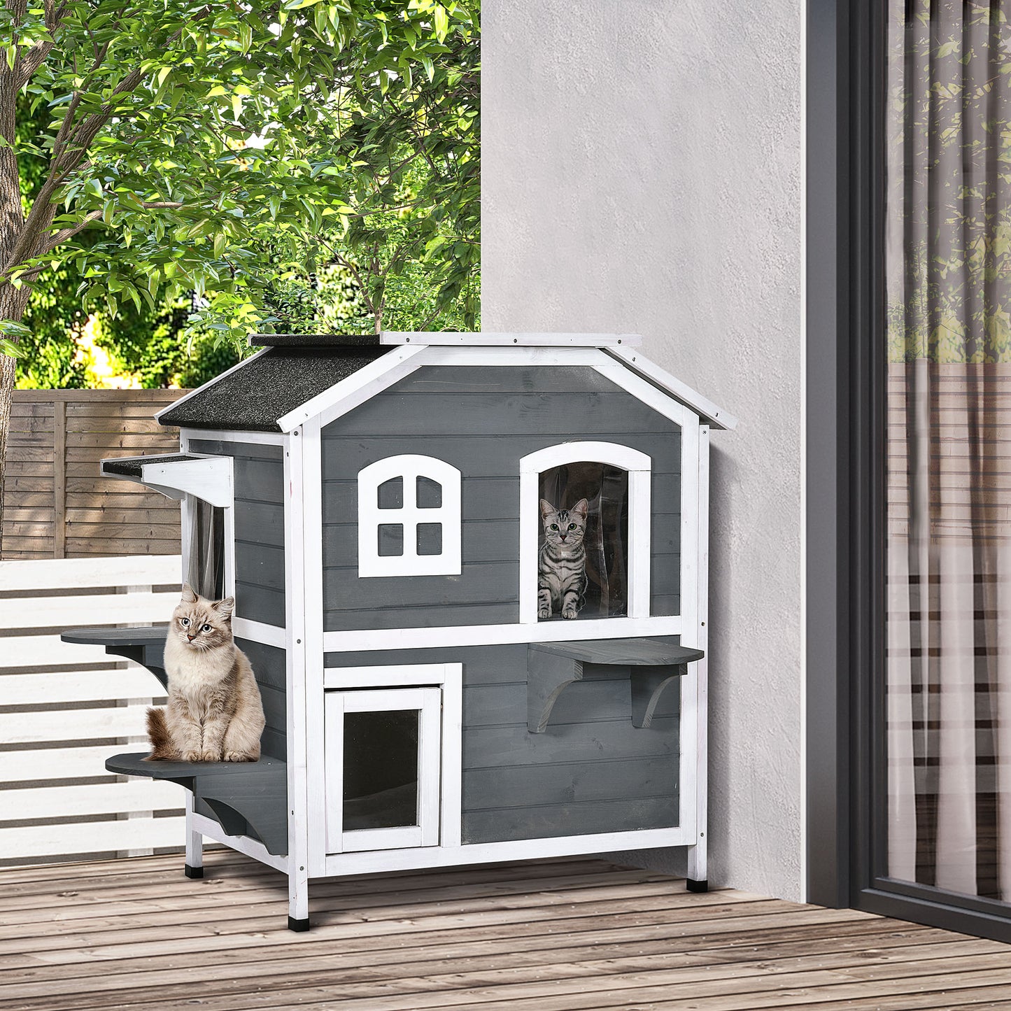 Gray wooden cat house with two levels and two cats lounging outside