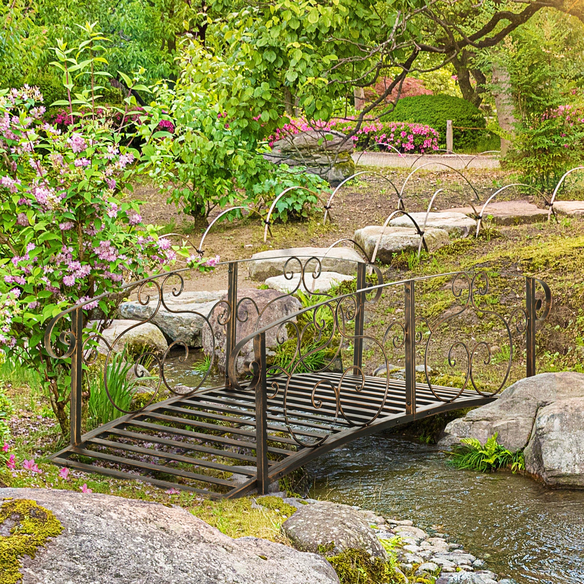 Ornate bronze garden bridge with decorative scrolls over a small stream