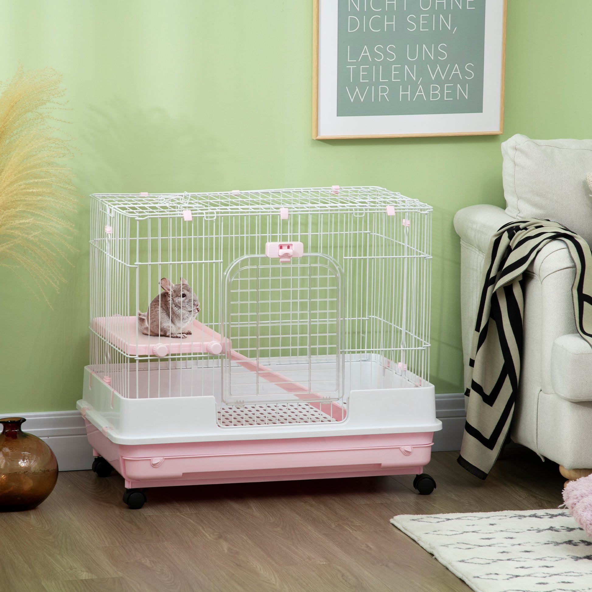 White and pink multilevel pet cage with wheels and a chinchilla resting on a pink platform