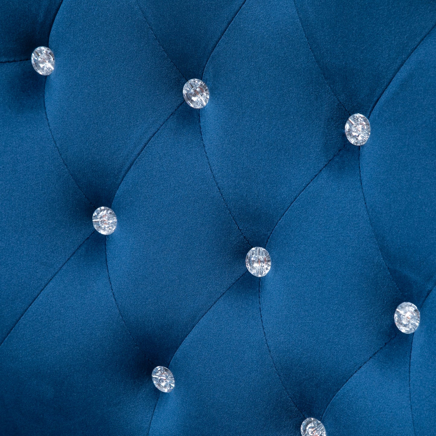 Closeup of royal blue velvet fabric with crystal diamond tufting detail