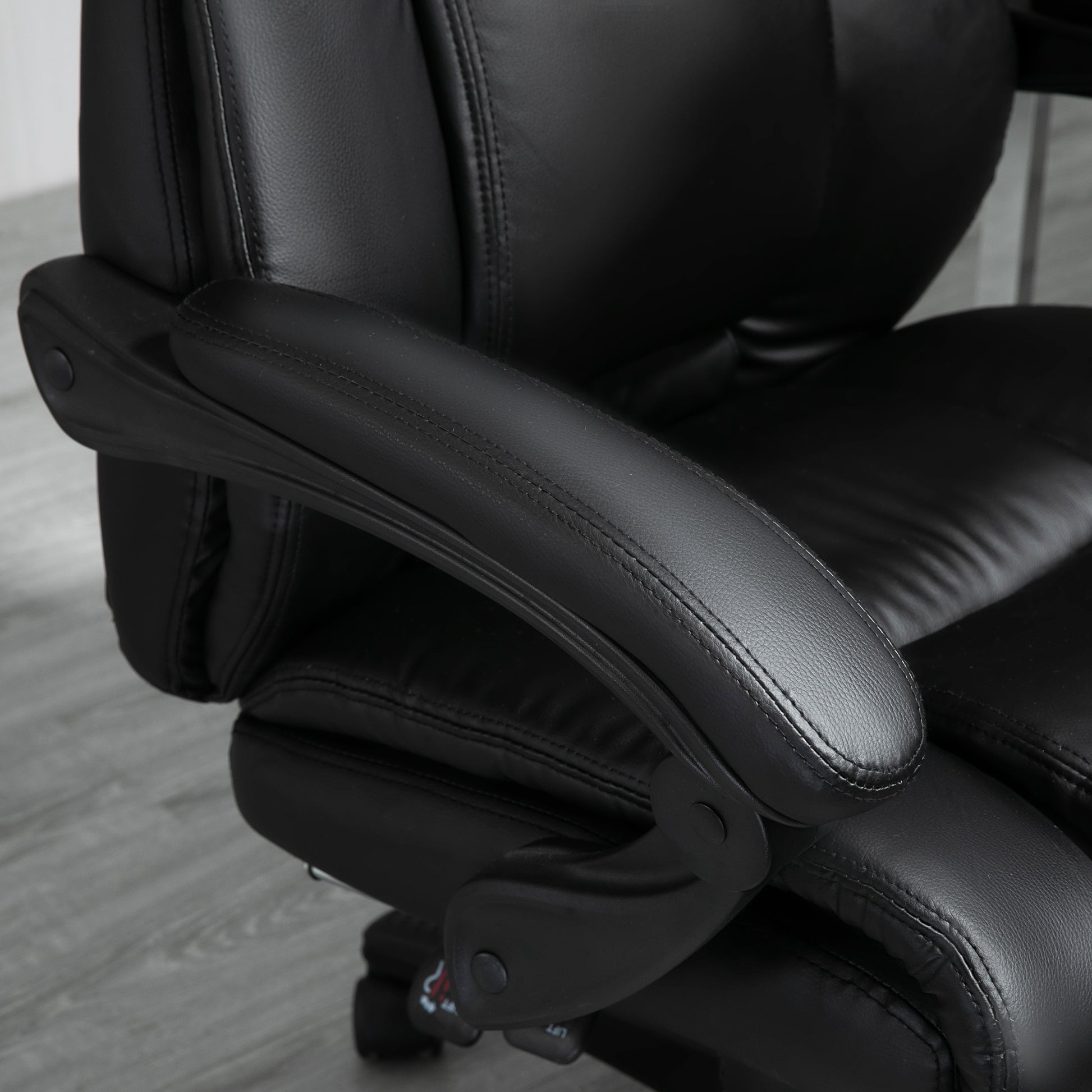 Closeup of black faux leather office chair armrest with detailed stitching