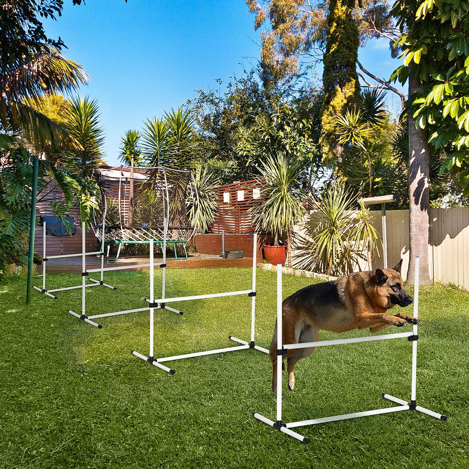 German Shepherd dog jumps over agility training hurdle in a backyard setting