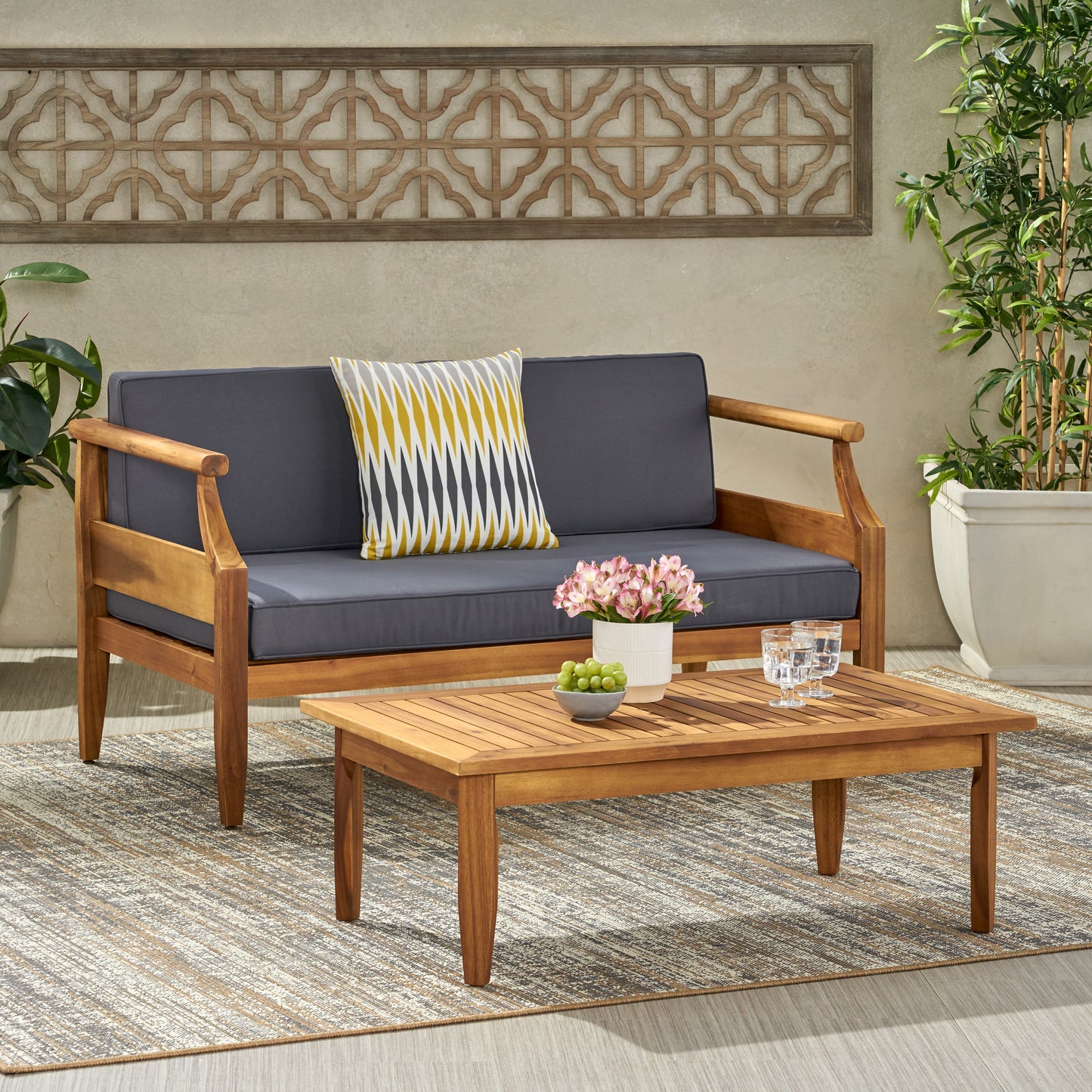 Wooden patio loveseat with dark gray cushions and geometric accent pillow
