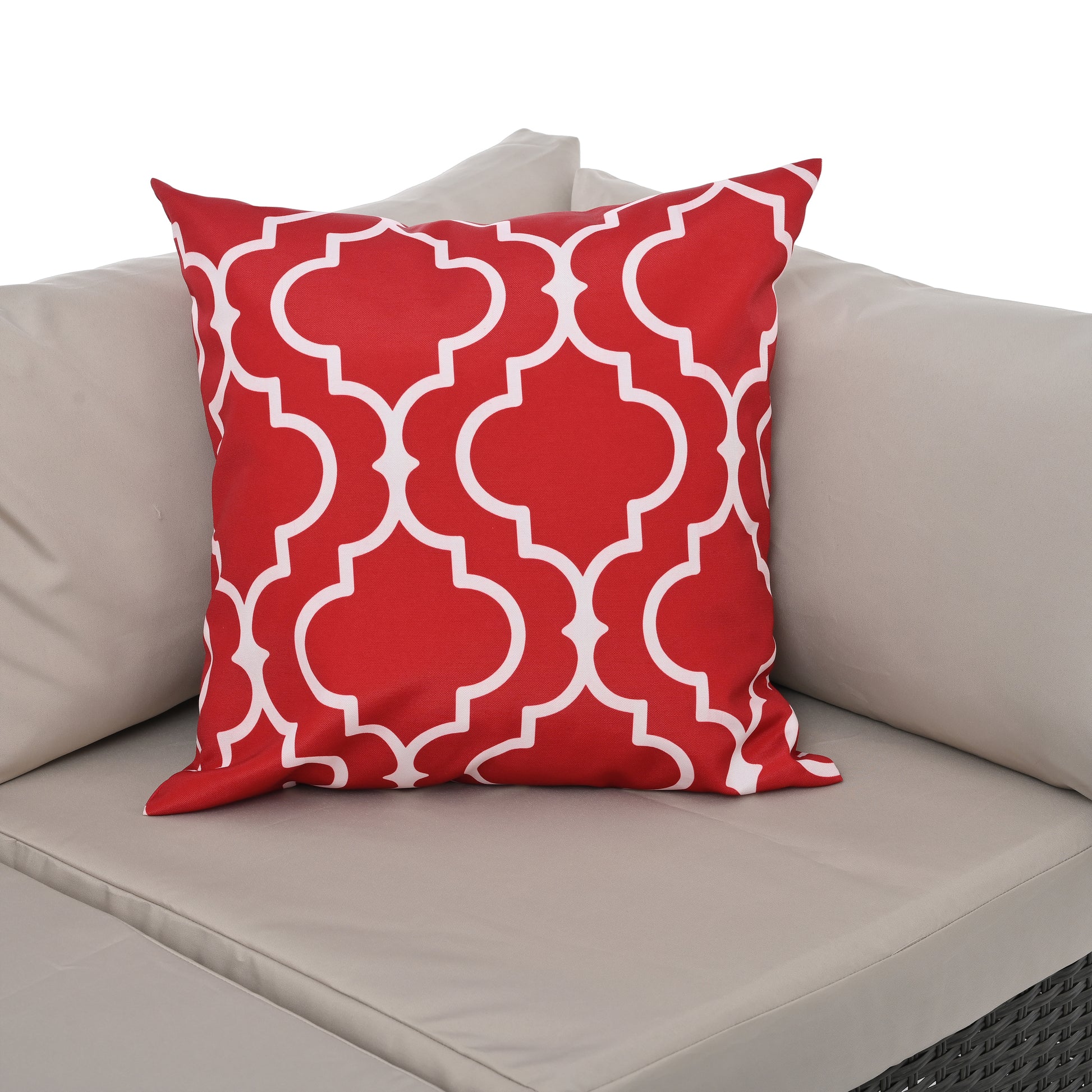 Red outdoor pillow with white quatrefoil pattern on a beige sectional couch