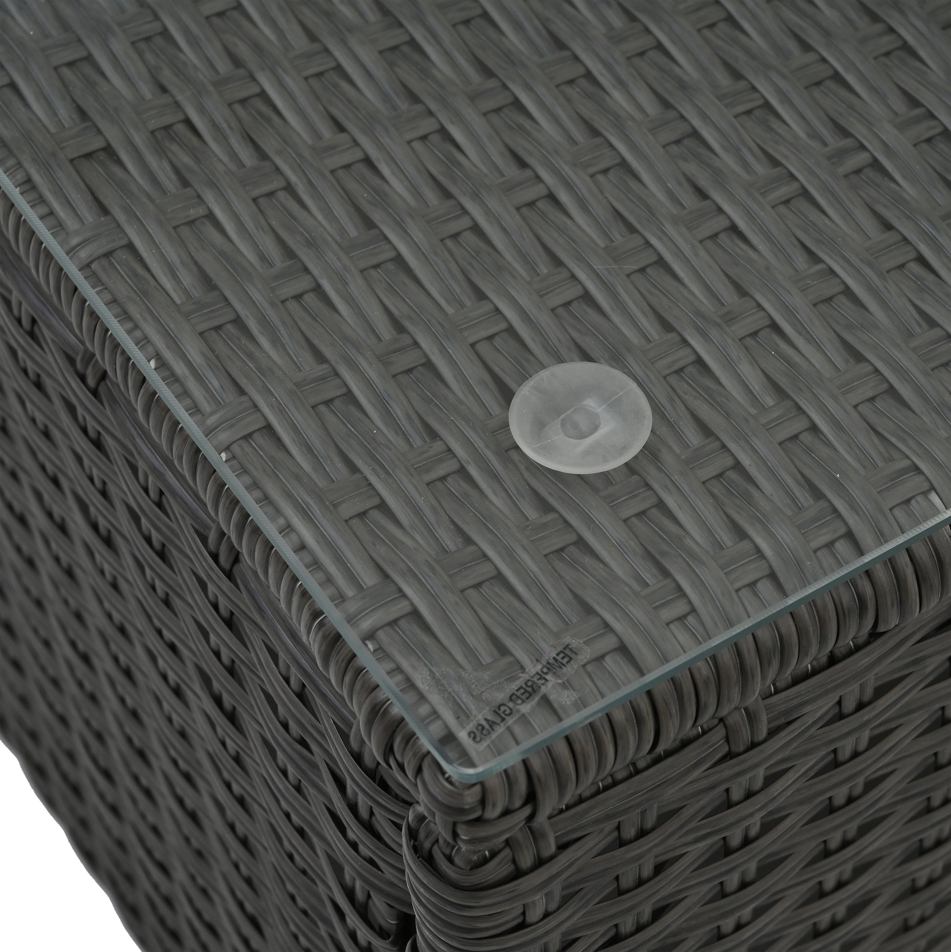 Closeup of dark gray woven wicker furniture with a clear glass top