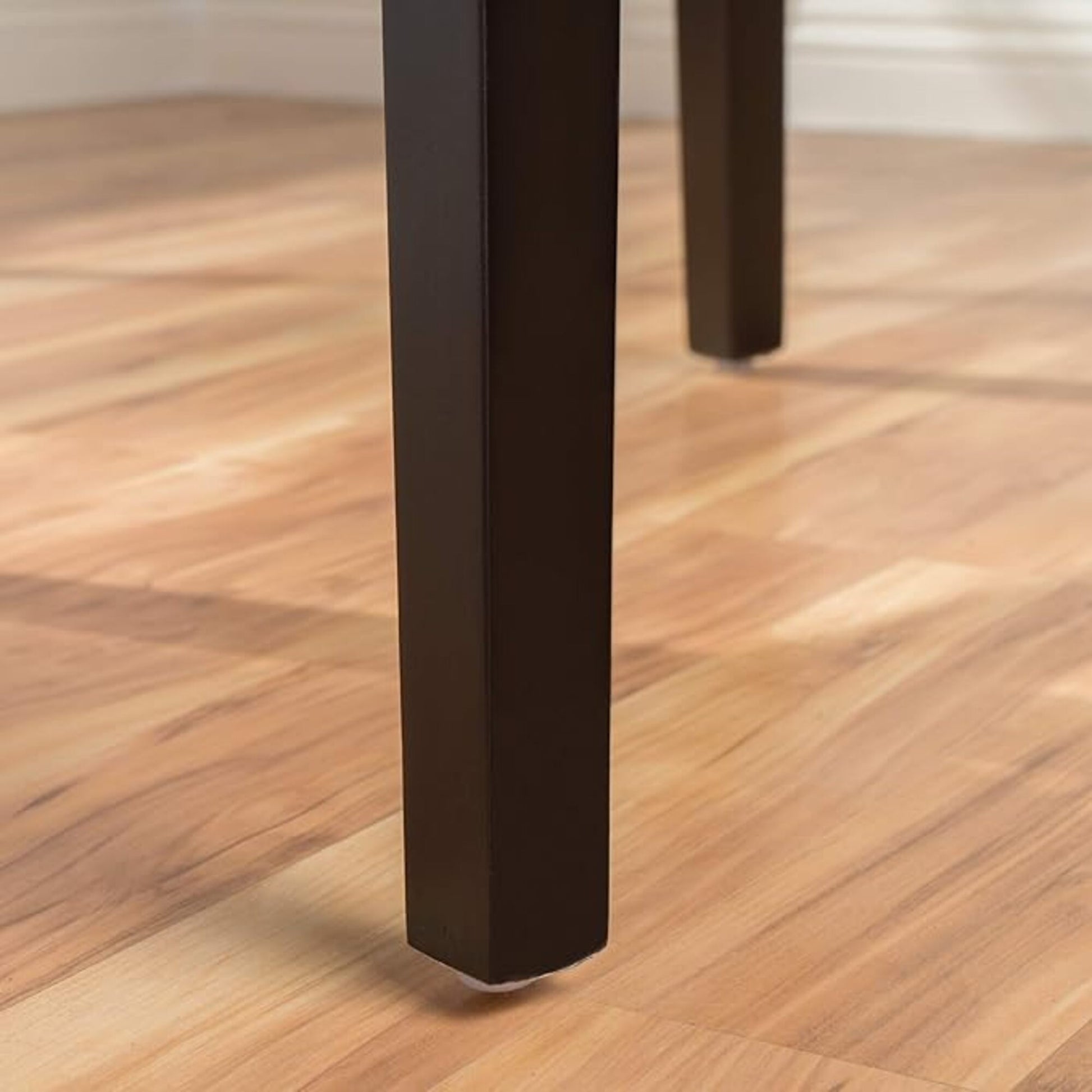 Closeup of dark brown wooden table legs on a light wood floor